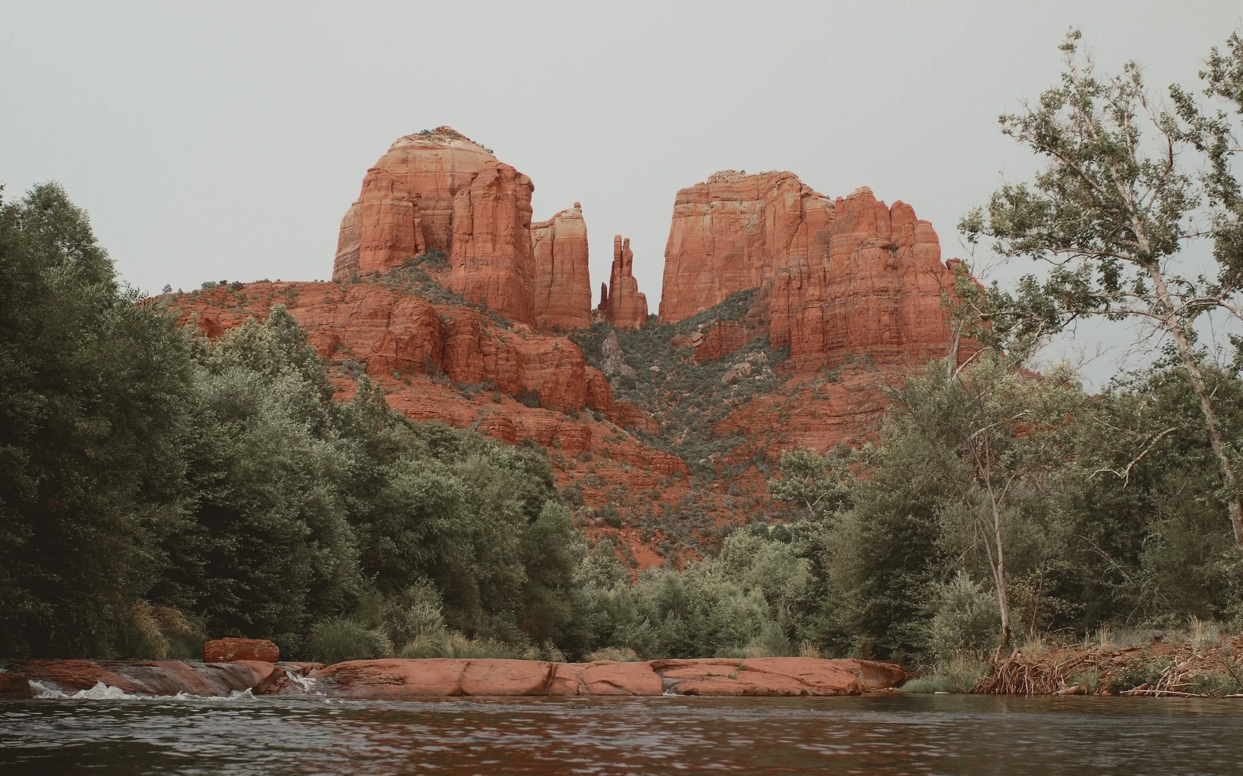 The red sandstone spires of Cathedral Rock rising above cottonwoods and Oak Creek at Red Rock Crossing in Sedona.