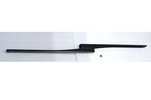 A long, black, flat object with a handle on one end, lying on a white surface, with a small, round brown item nearby.