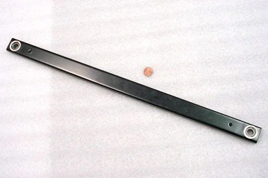 A metal ruler and a penny on a light-colored surface.