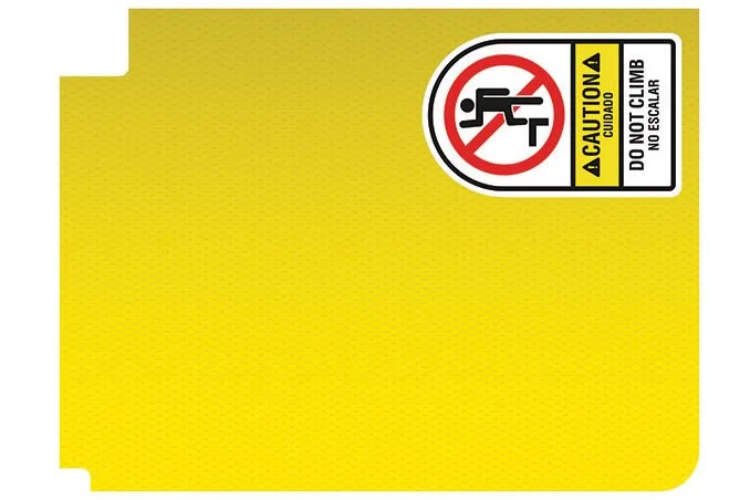 Close-up of a yellow safety sign with a warning label in English and Spanish, and a symbol indicating no climbing or sitting on the structure.