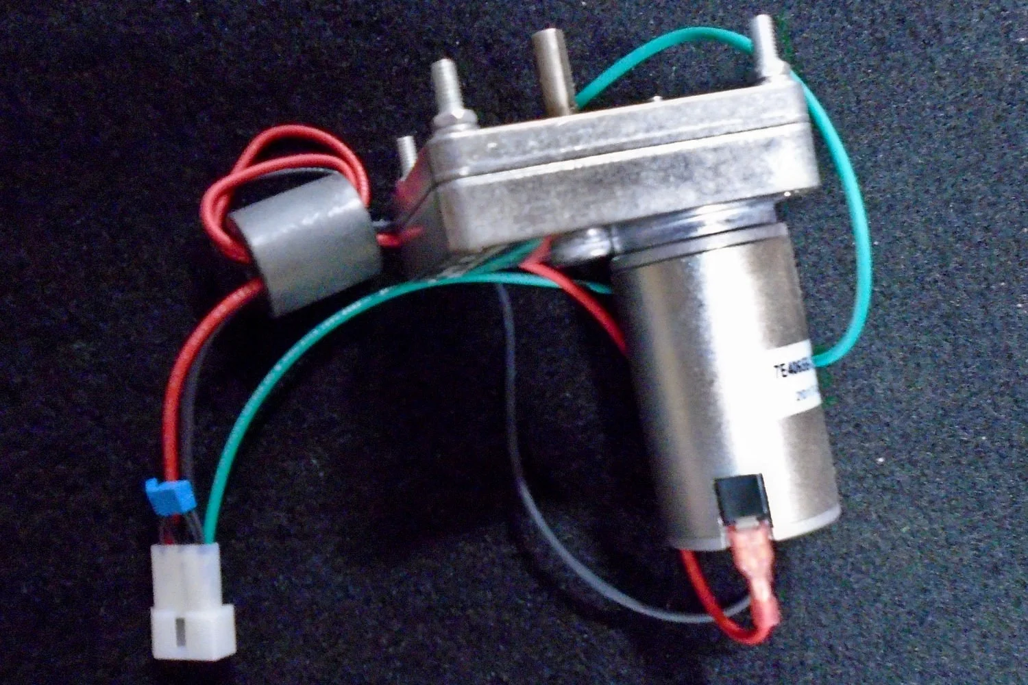 Electric motor with wires and connectors on a black surface.