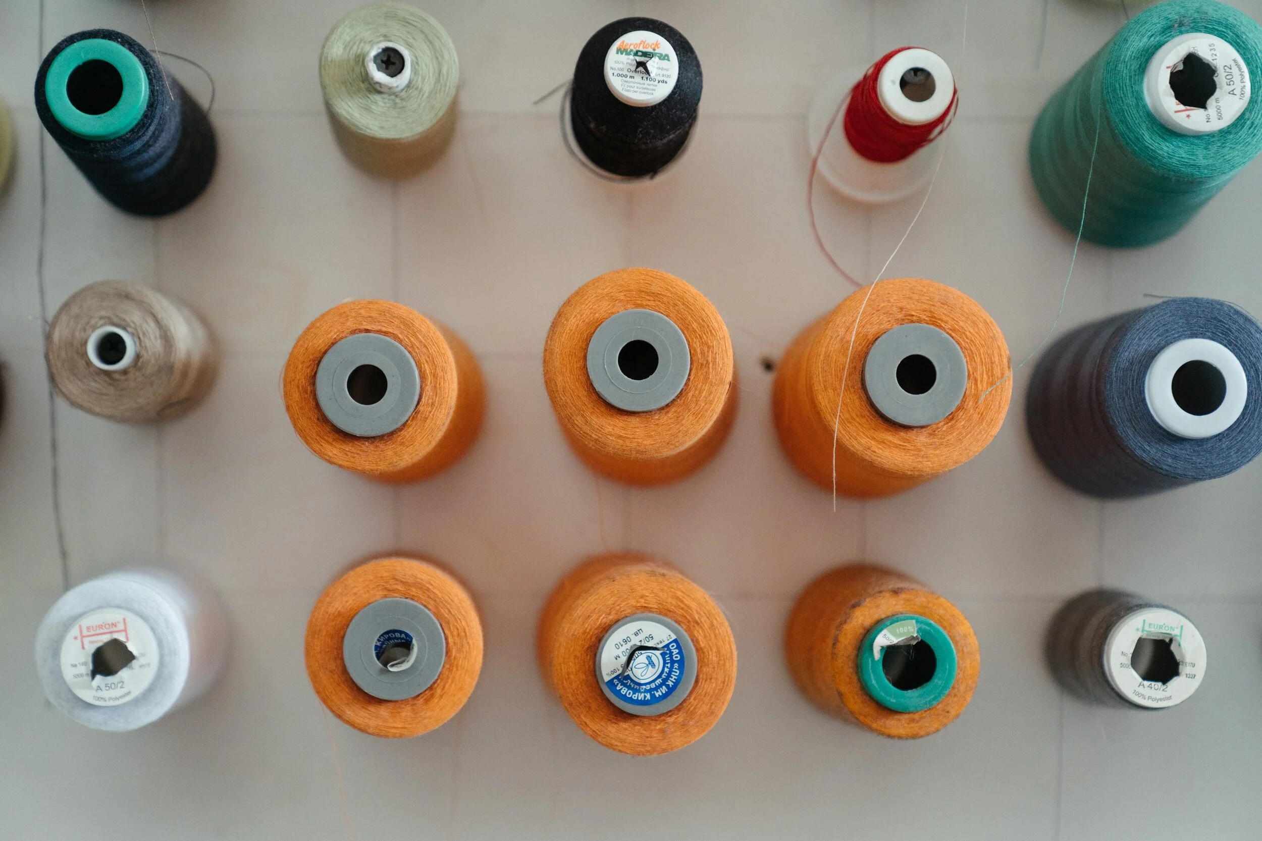 Various colored spools of thread arranged on a white surface.