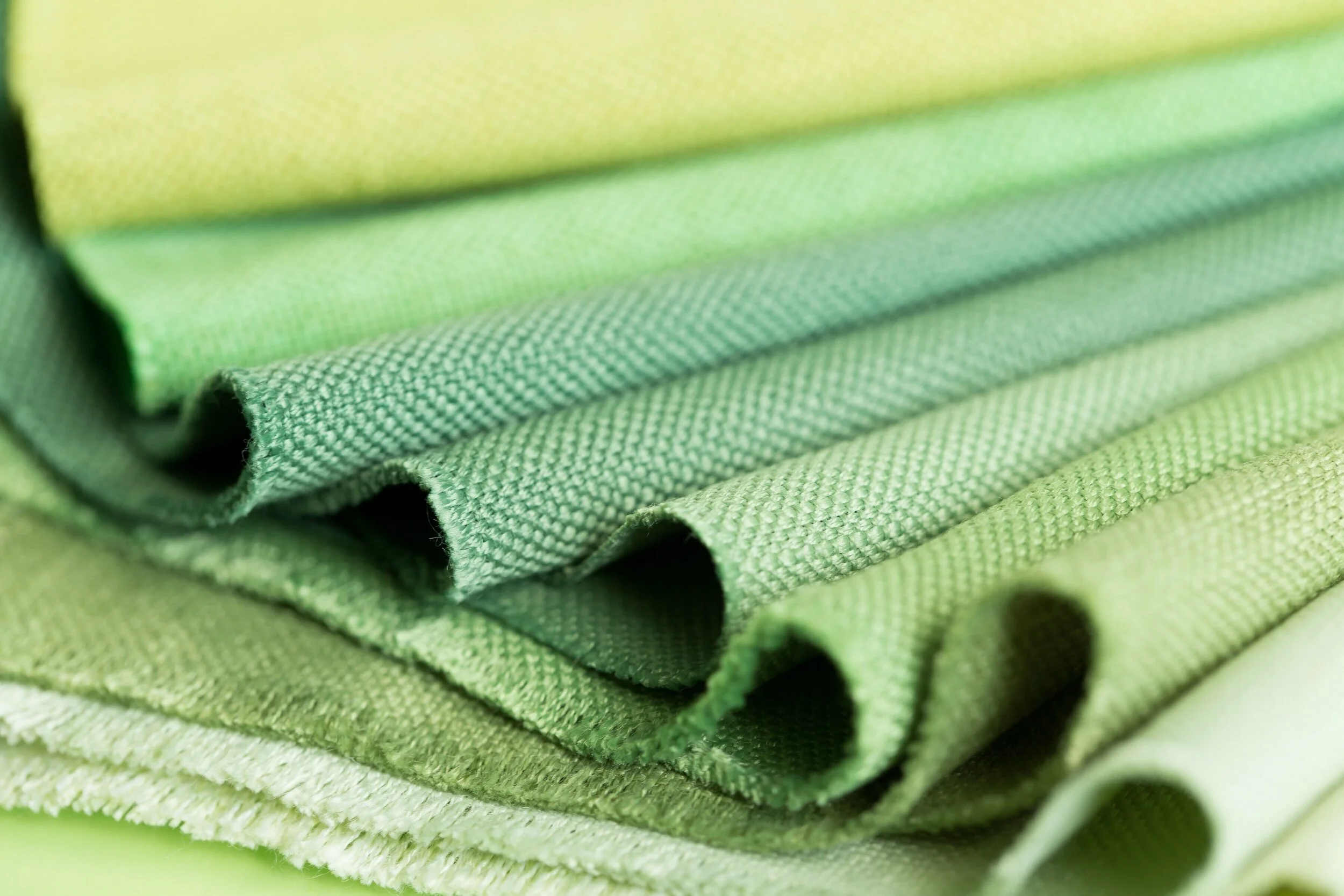 Stack of green fabric swatches in various shades.