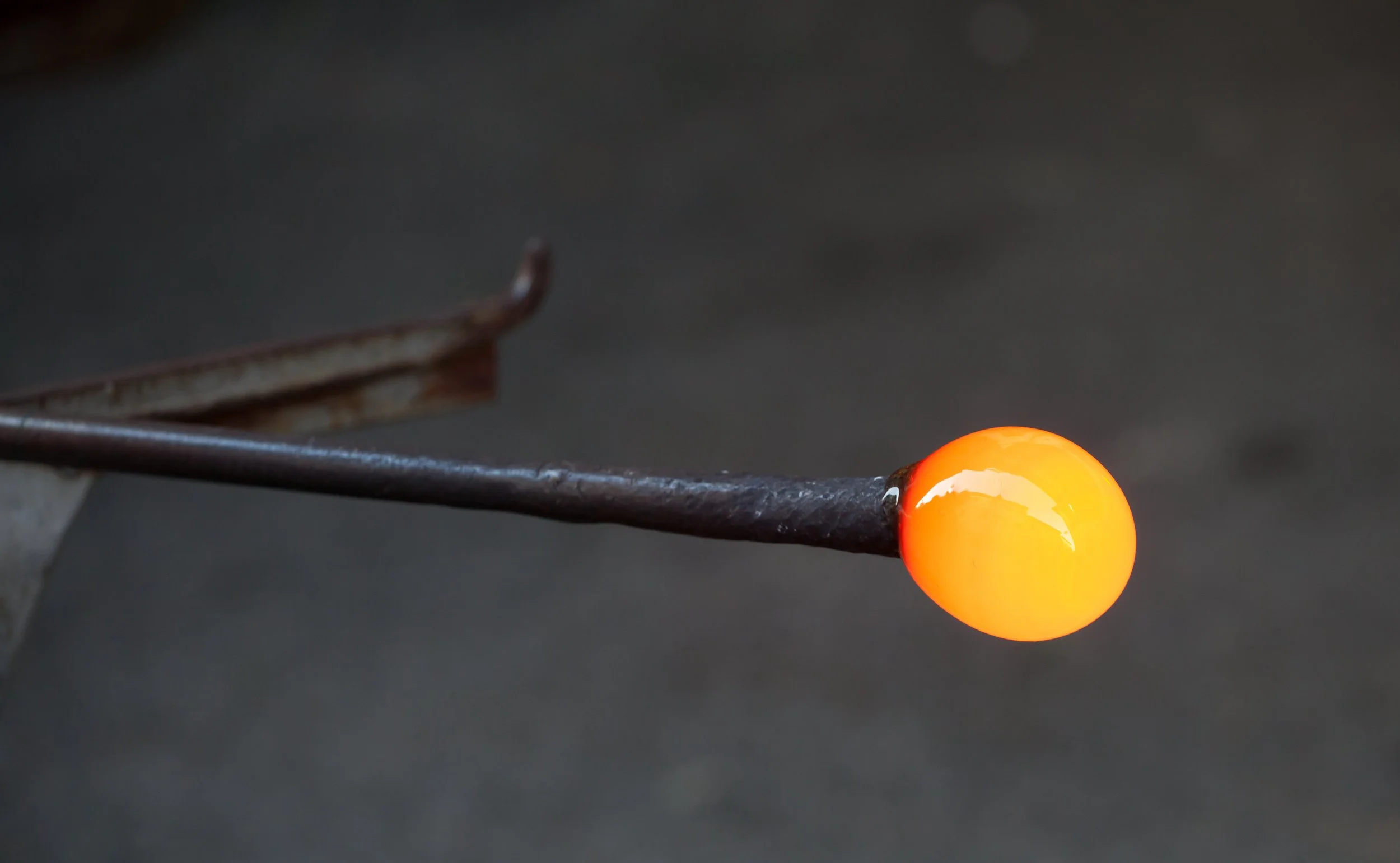Molten glass on the end of a metal rod during glassblowing.