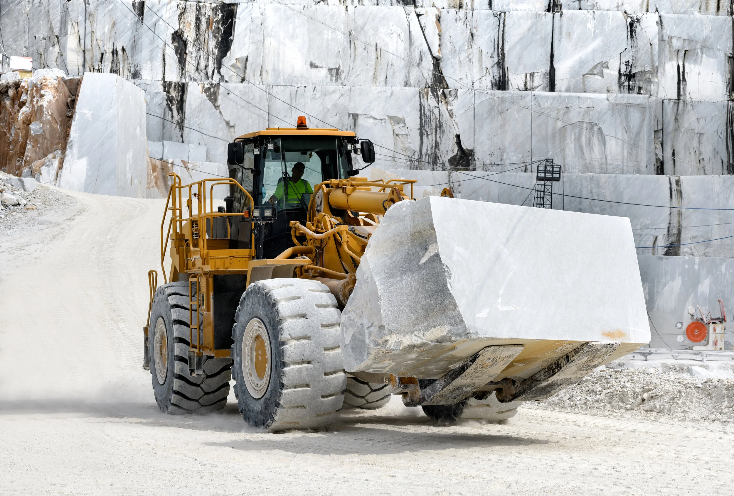 Front loader moving large marble block in quarry