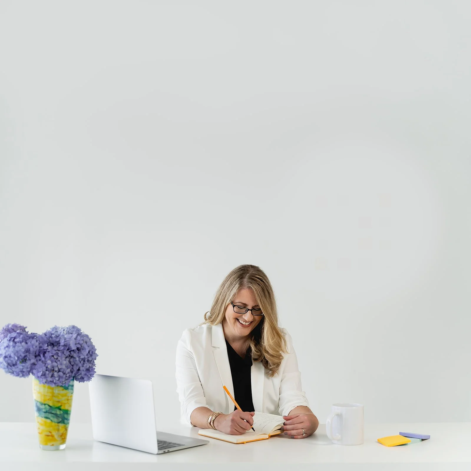 Karen Eber writing at a desk with purple hydrangeas