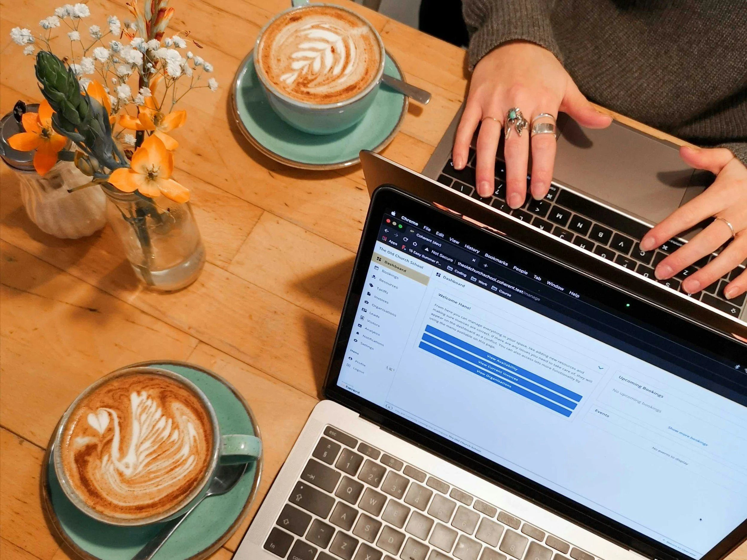 Stock image looking down at two laptops and cafe lattes, while one person is typing.