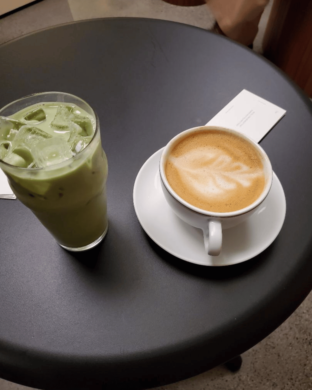 Cafe matcha and latte on a round brown cafe table.