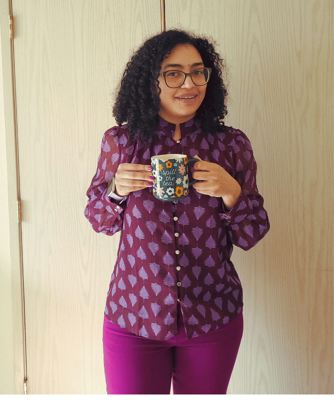 Isabelle standing with a mug and smiling, while wearing a vibrate purple.