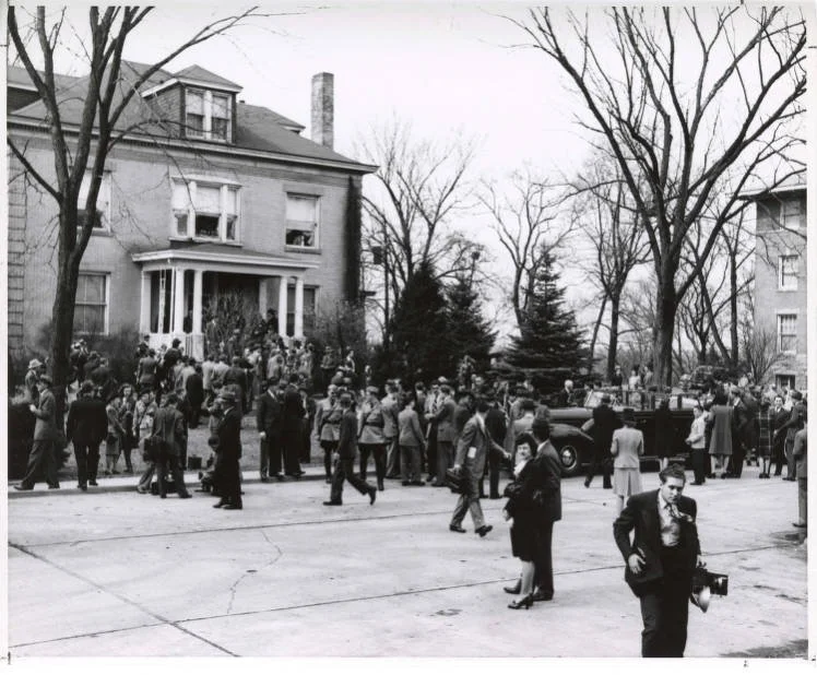 A large group of people stand outside a building waiting to be let in.