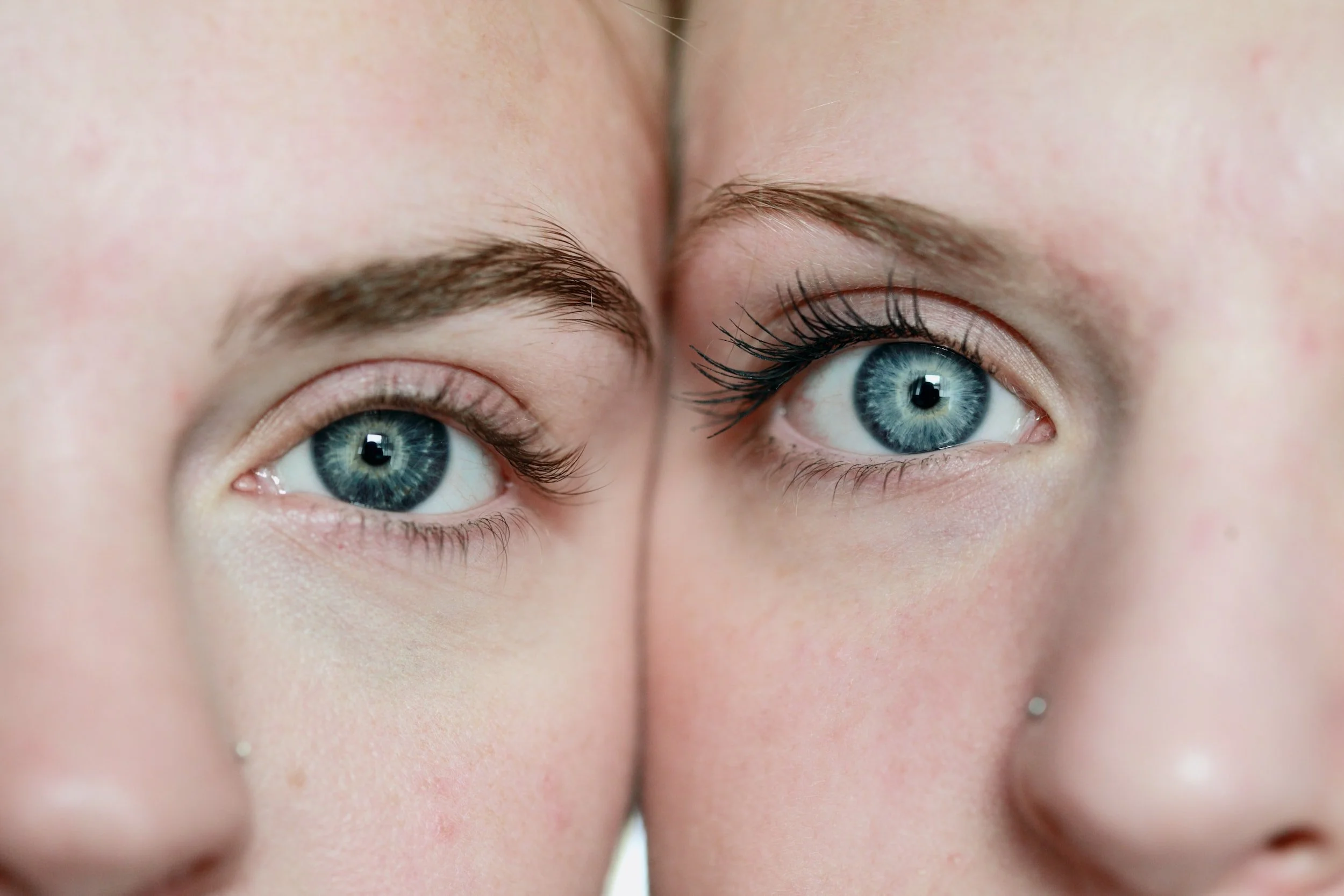 Close-up of two faces with blue eyes and light skins, showing eyebrows and noses.