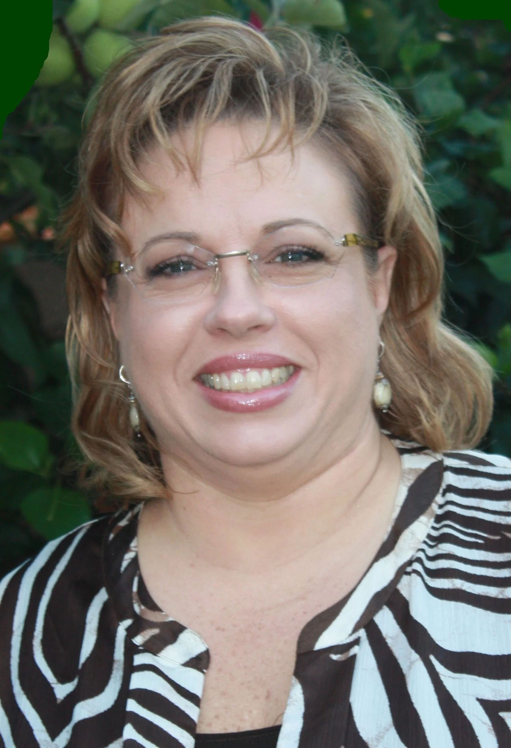 headshot of laurie with a brown striped shirt with a green background of foliage
