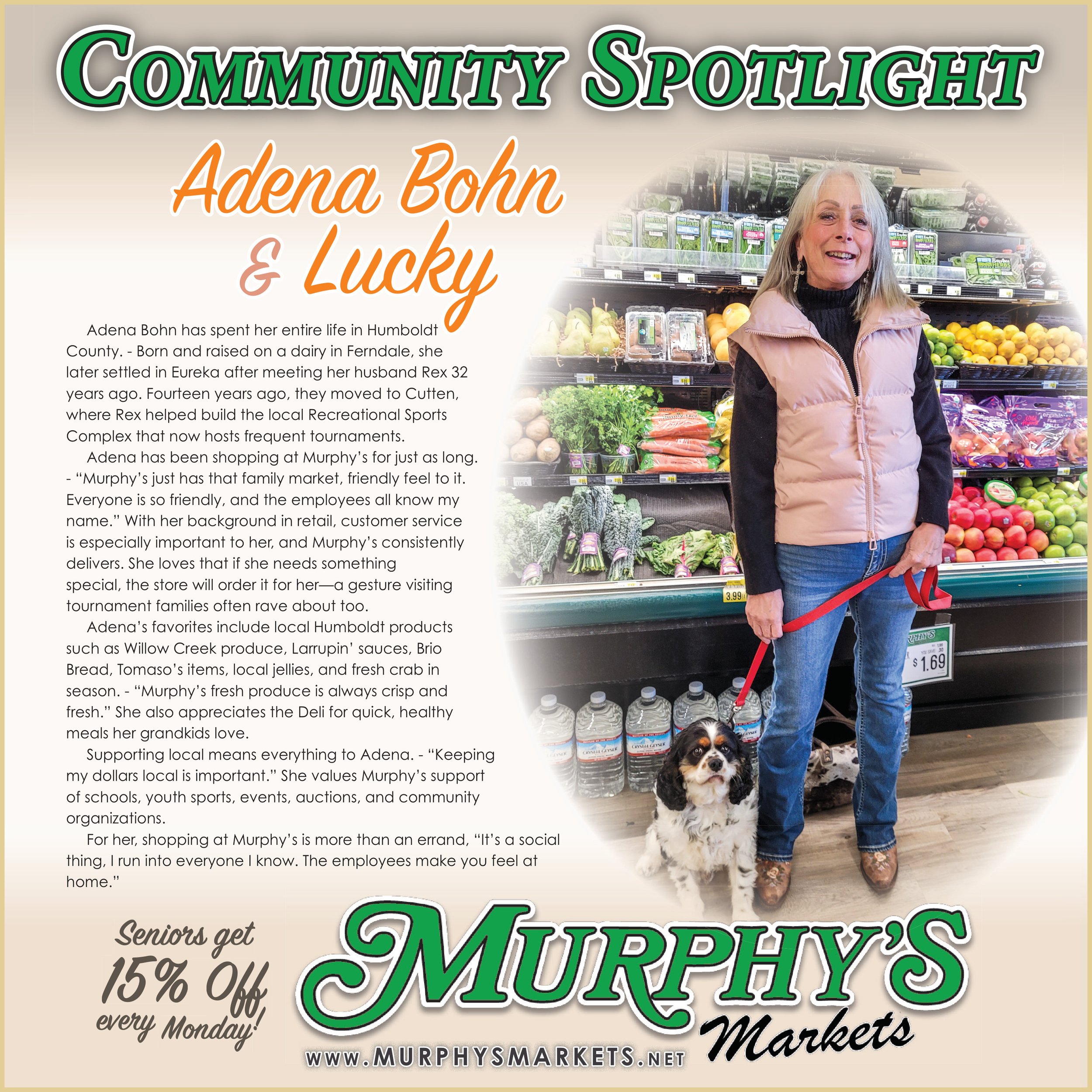 A woman standing inside Murphy's Market, holding a leash with a small dog, next to a display of fresh produce including vegetables and fruits.