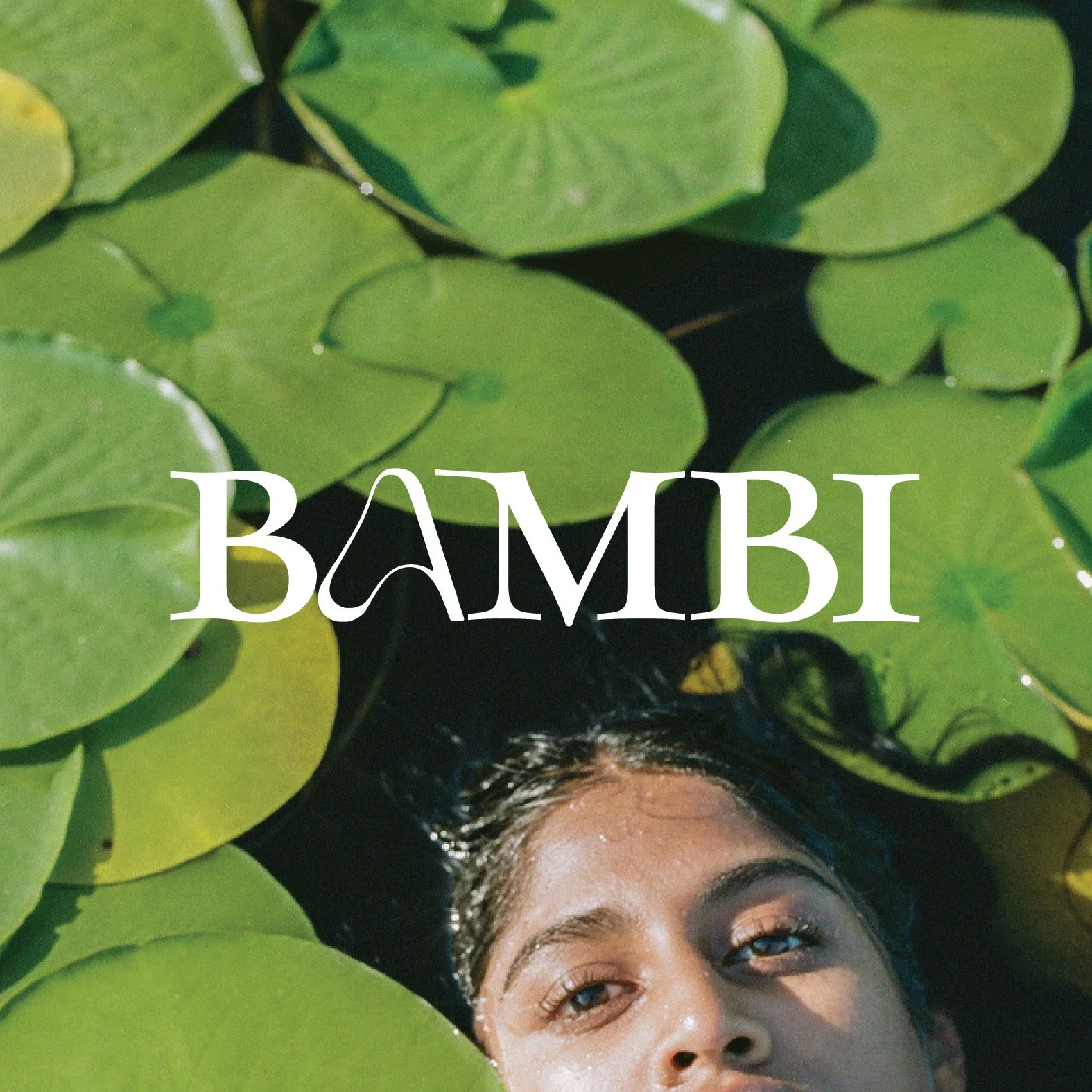 Close-up of a woman's face partially submerged in water with green lily pads and the word 'BAMBI' in white text overlay.