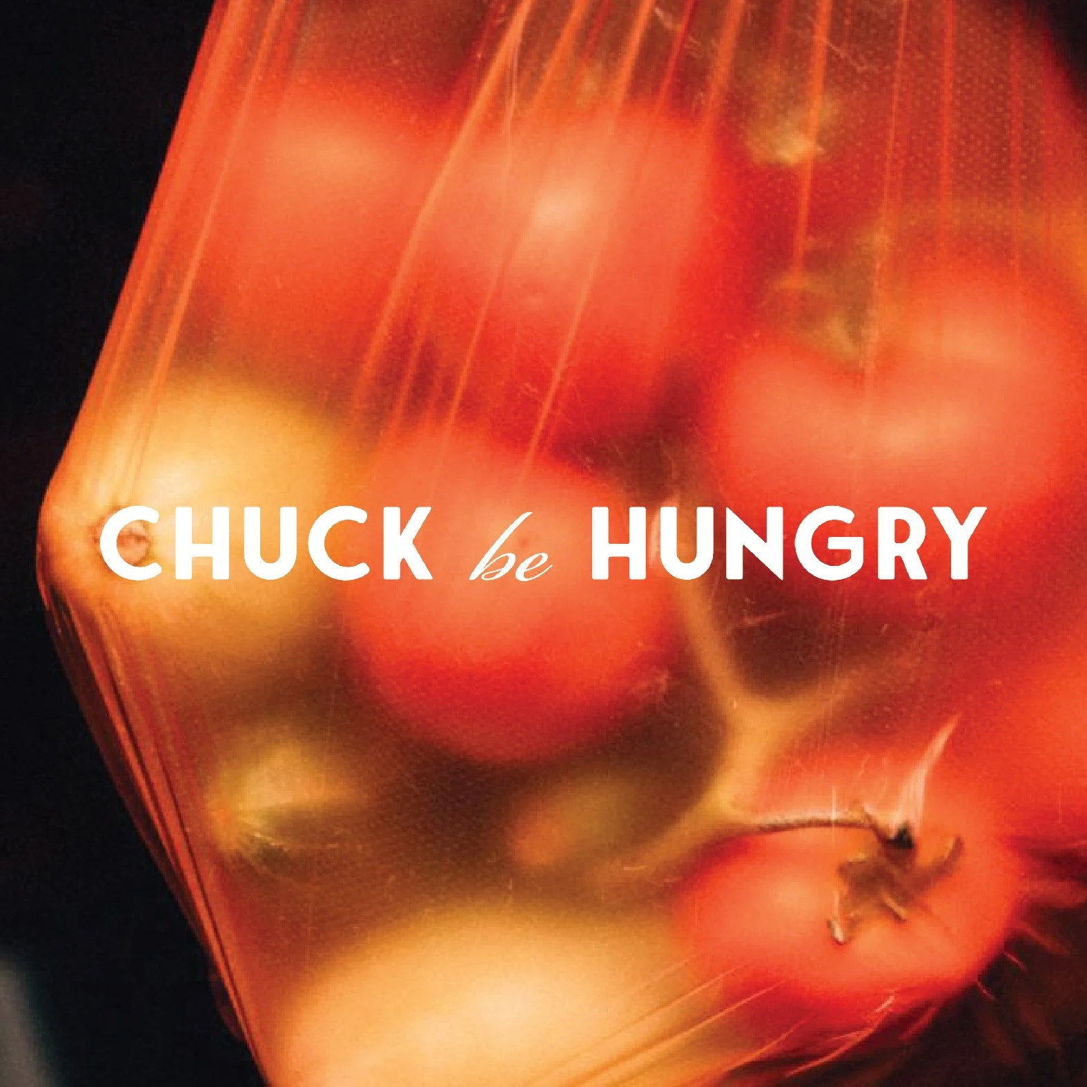 Close-up of a glass of orange-colored beverage with some red and green fruit pieces inside, with the text "Chuck be hungry" overlaid.