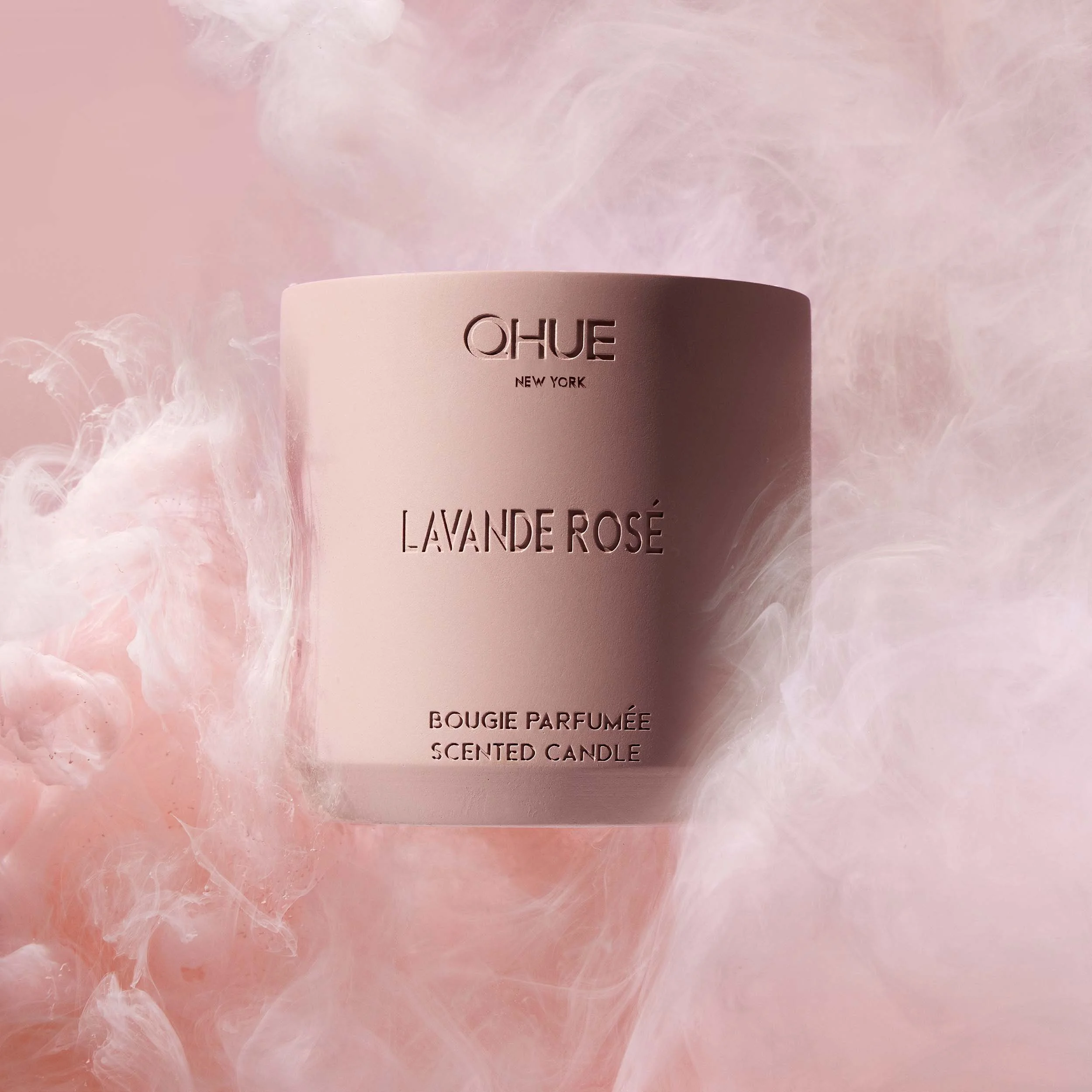 Qhue New York Lavande Rosé scented candle in a blush pink cement vessel surrounded by soft pink floral-inspired smoke.