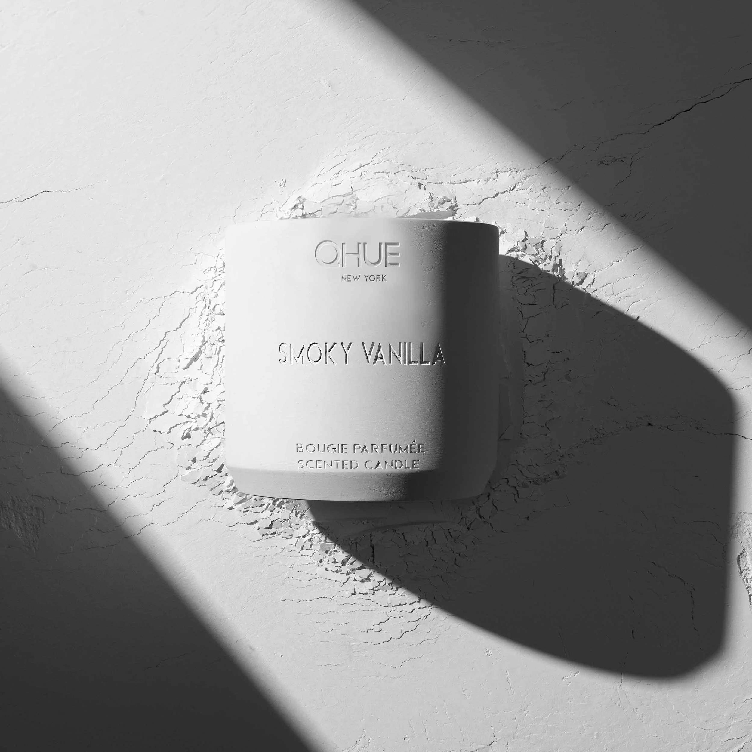 Qhue New York Smoky Vanilla scented candle in a hand-painted white cement vessel with minimalist architectural styling.