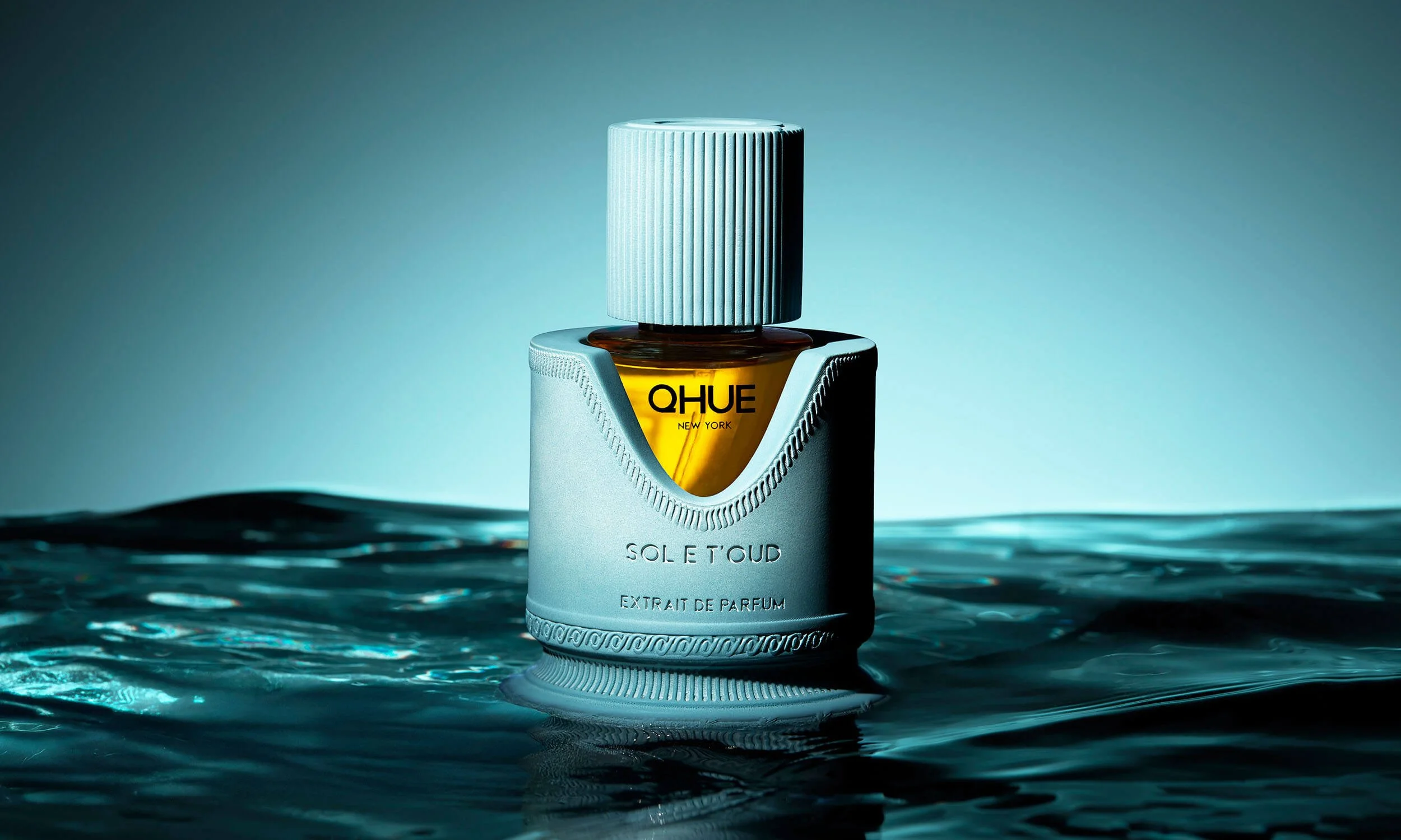 Luxury oud fragrance Sol E T’oud by Qhue New York photographed emerging from water, symbolizing a bright radiant interpretation of oud.