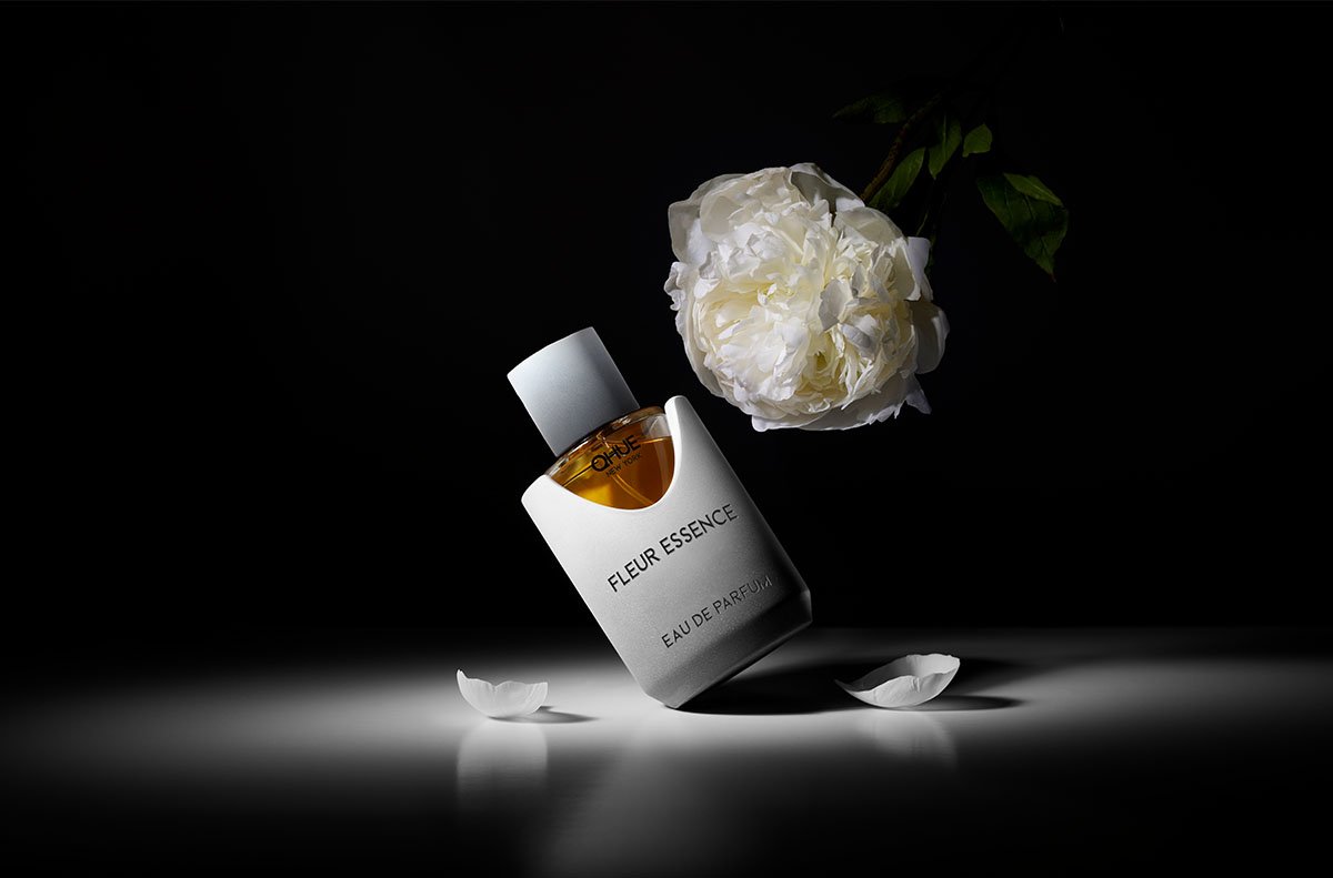 Fleur Essence by Qhue New York in a sculptural cement vessel, photographed in moody light to evoke modern floral sensuality.