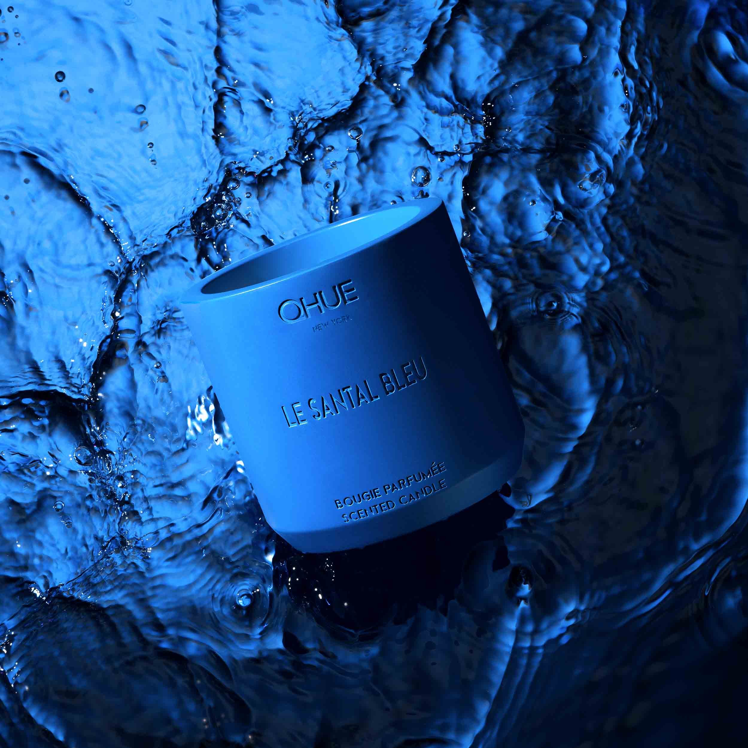 Qhue New York Le Santal Bleu scented candle in a cobalt blue cement vessel surrounded by flowing water and ice-inspired textures.