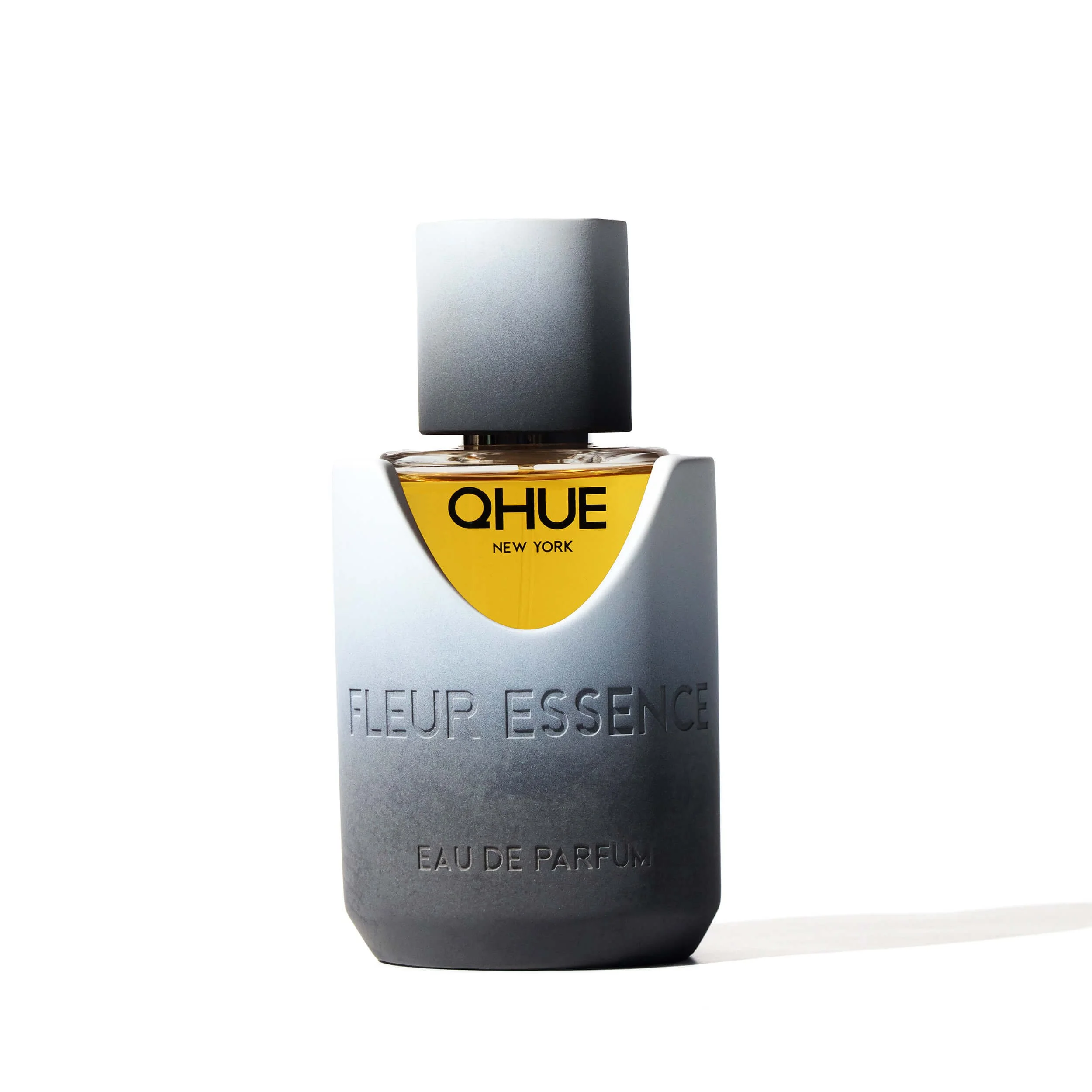Fleur Essence Eau de Parfum by Qhue New York, a soft floral fragrance bottle with warm golden liquid and sculpted cement vessel