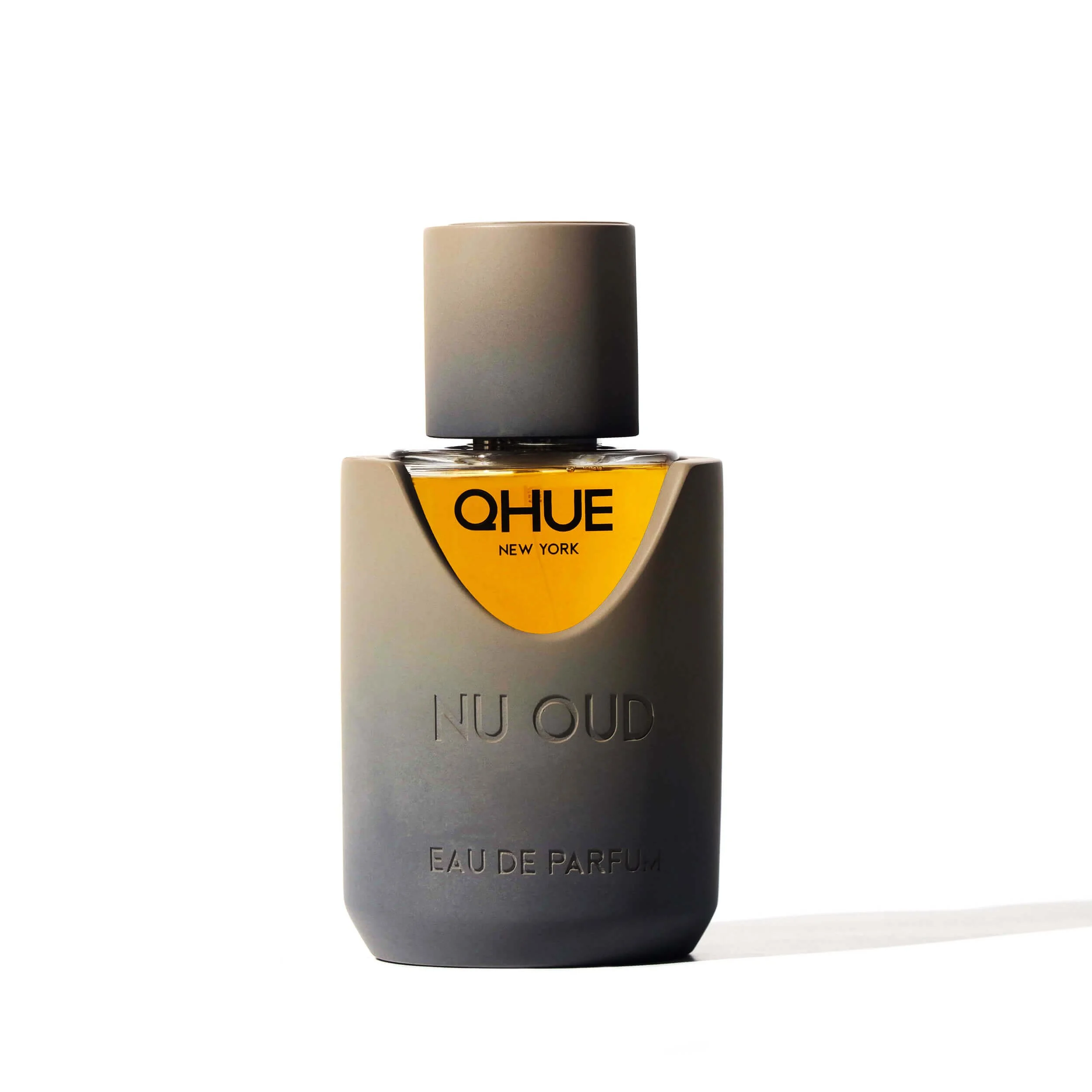 Nu Oud by Qhue New York extrait de parfum bottle in soft golden lighting, featuring a sculpted matte vessel with rich amber highlights.