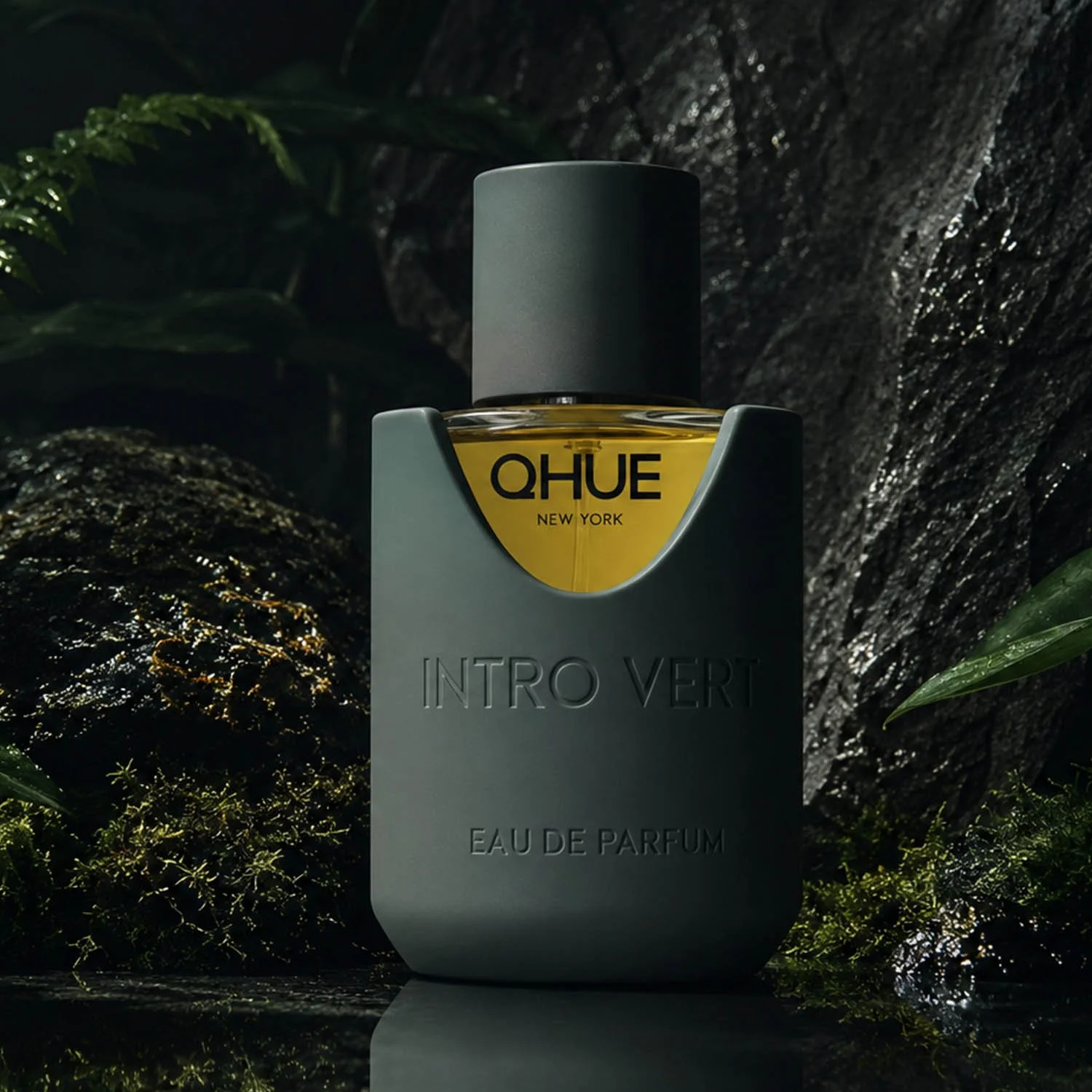 Qhue New York Intro Vert Eau de Parfum luxury fragrance bottle displayed among moss, stone, and lush greenery in a moody forest-inspired campaign.