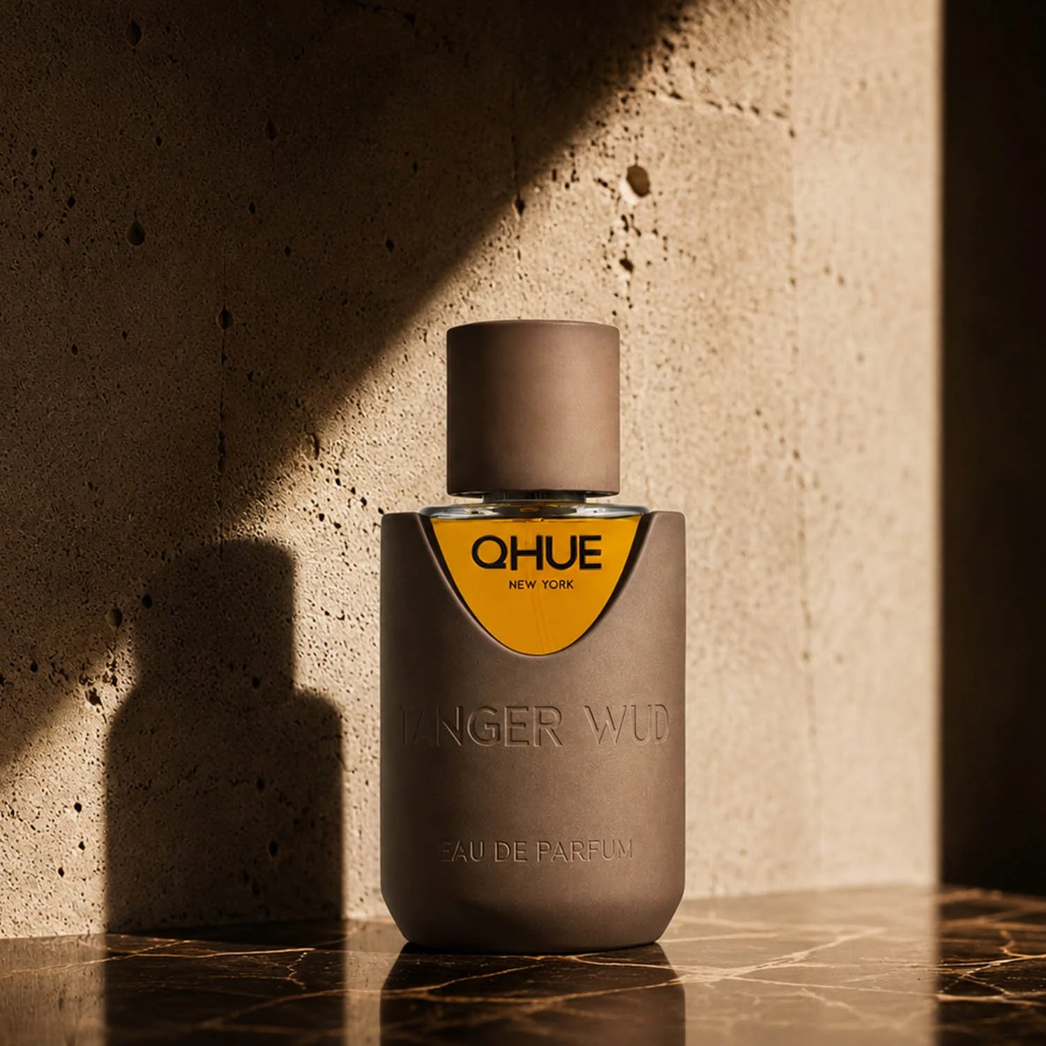 Qhue New York Tanger Wud Eau de Parfum in a warm architectural setting with dramatic sunlight and marble surface.