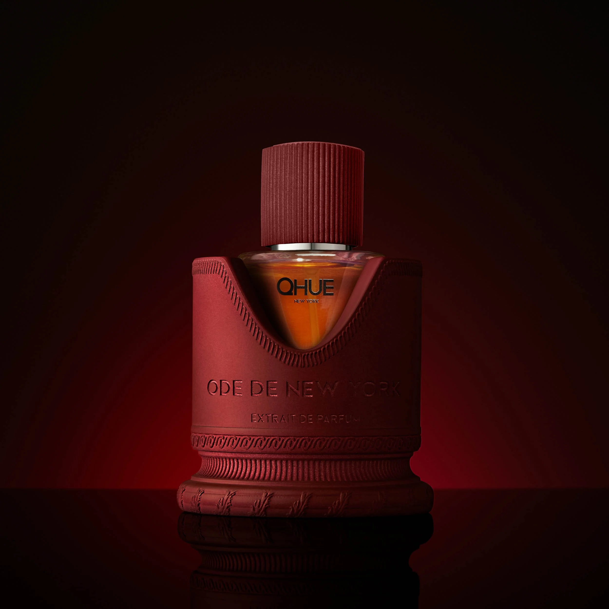 Qhue New York Ode de New York Extrait de Parfum luxury fragrance on a dark red background with dramatic lighting.