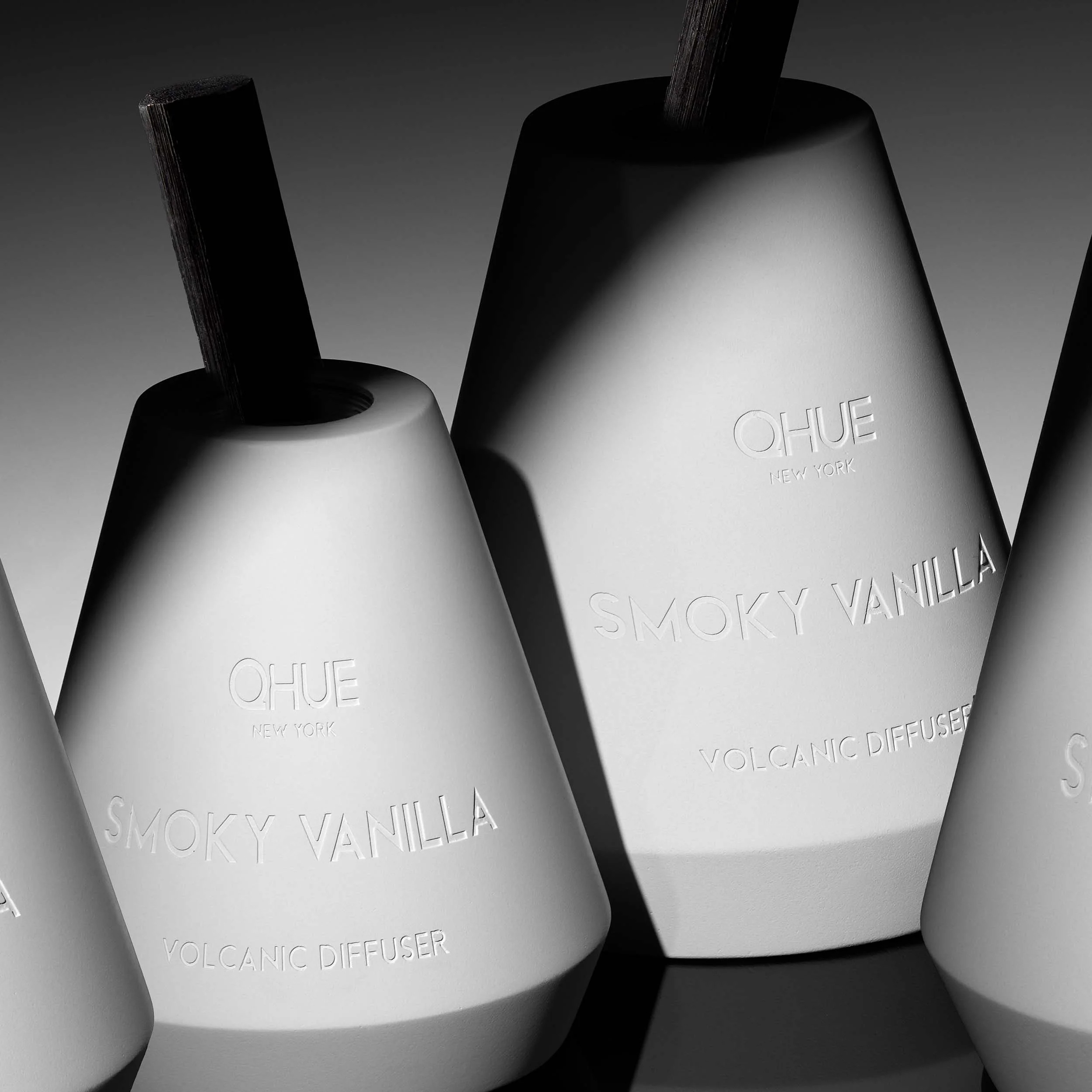 Qhue New York Smoky Vanilla Volcanic Reed Diffuser in a hand-painted white cement vessel with signature black bamboo reed.