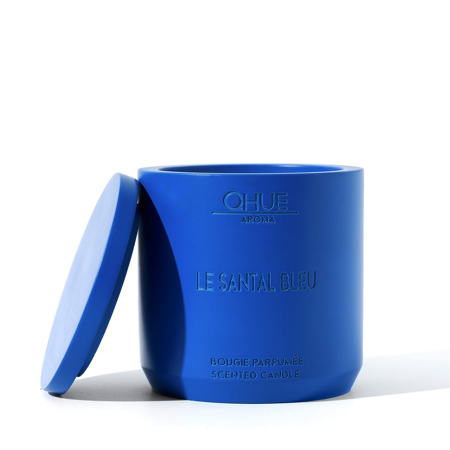 Le Santal Bleu candle featuring a sleek design with a deep blue hue, elegantly presented with a flickering flame, exuding the warm, exotic aroma of sandalwood and spices