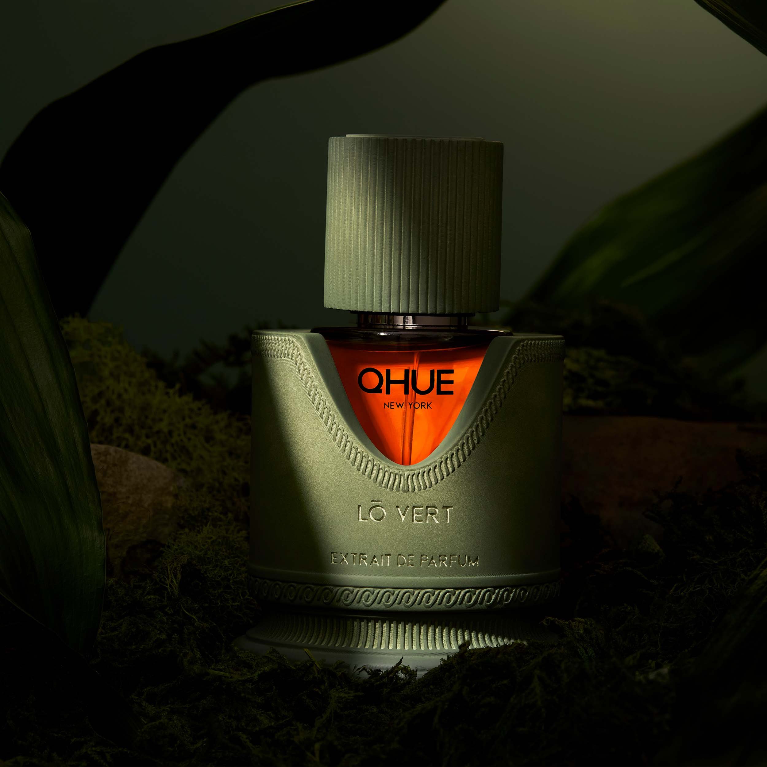 Qhue New York Lō Vert Extrait de Parfum luxury fragrance surrounded by lush greenery and moss.