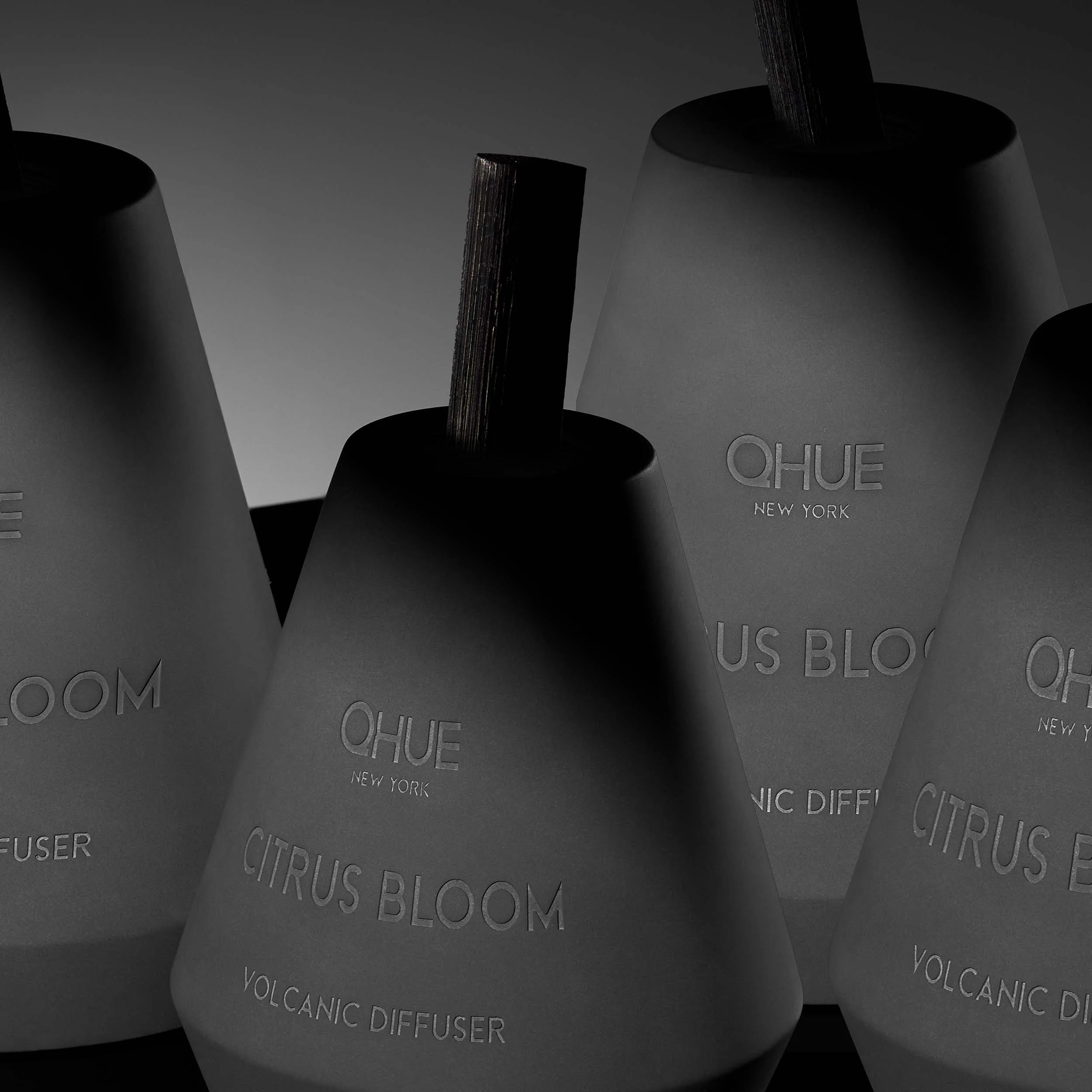 Qhue New York Citrus Bloom Volcanic Reed Diffusers in matte cement vessels.