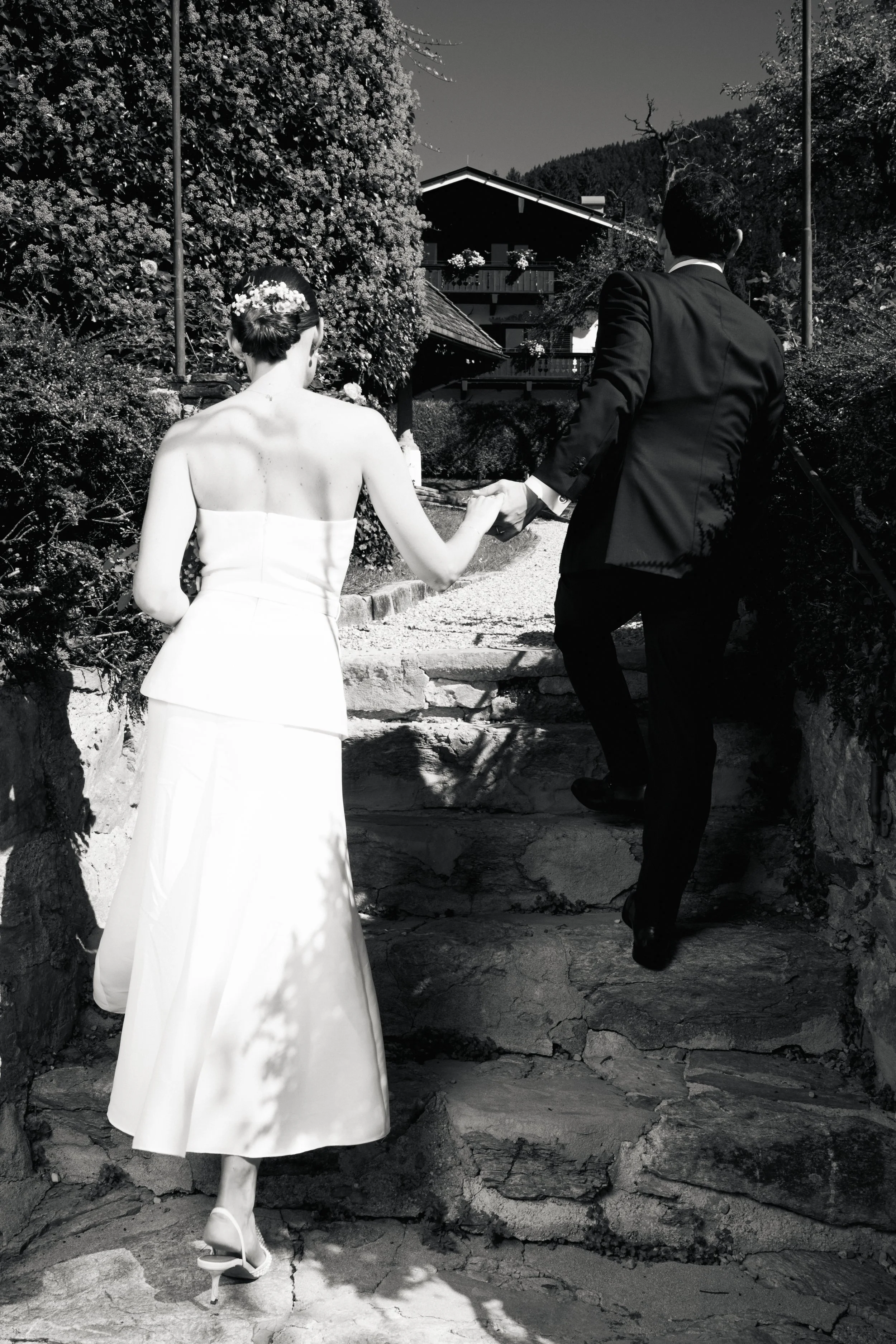 Ein Brautpaar, das die Treppe hinaufgeht, auf dem Weg zu einer Hochzeit, aufgenommen in Schwarz-Weiß.