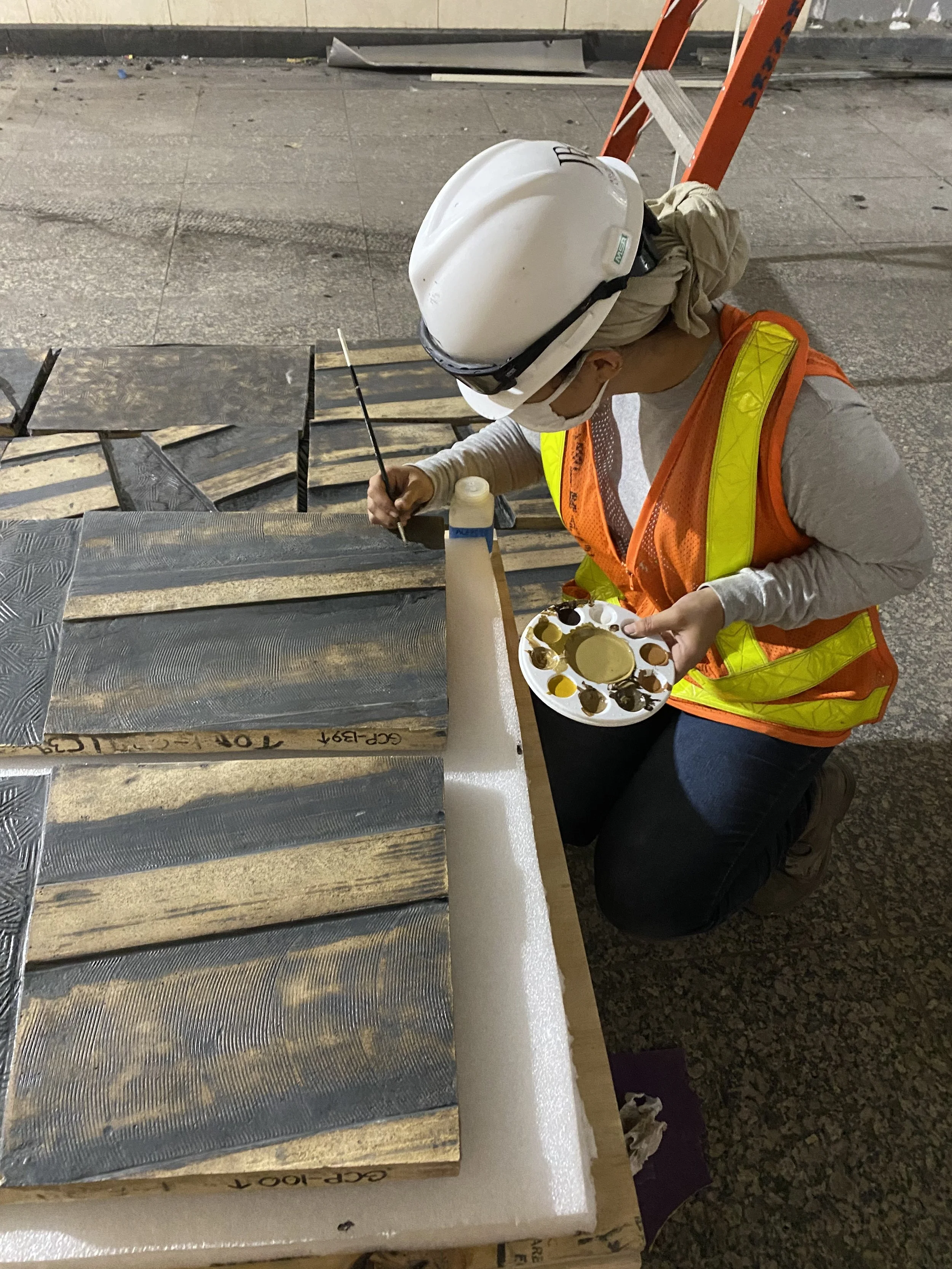 A conservator in-paints terra cotta mural panels removed for relocation.