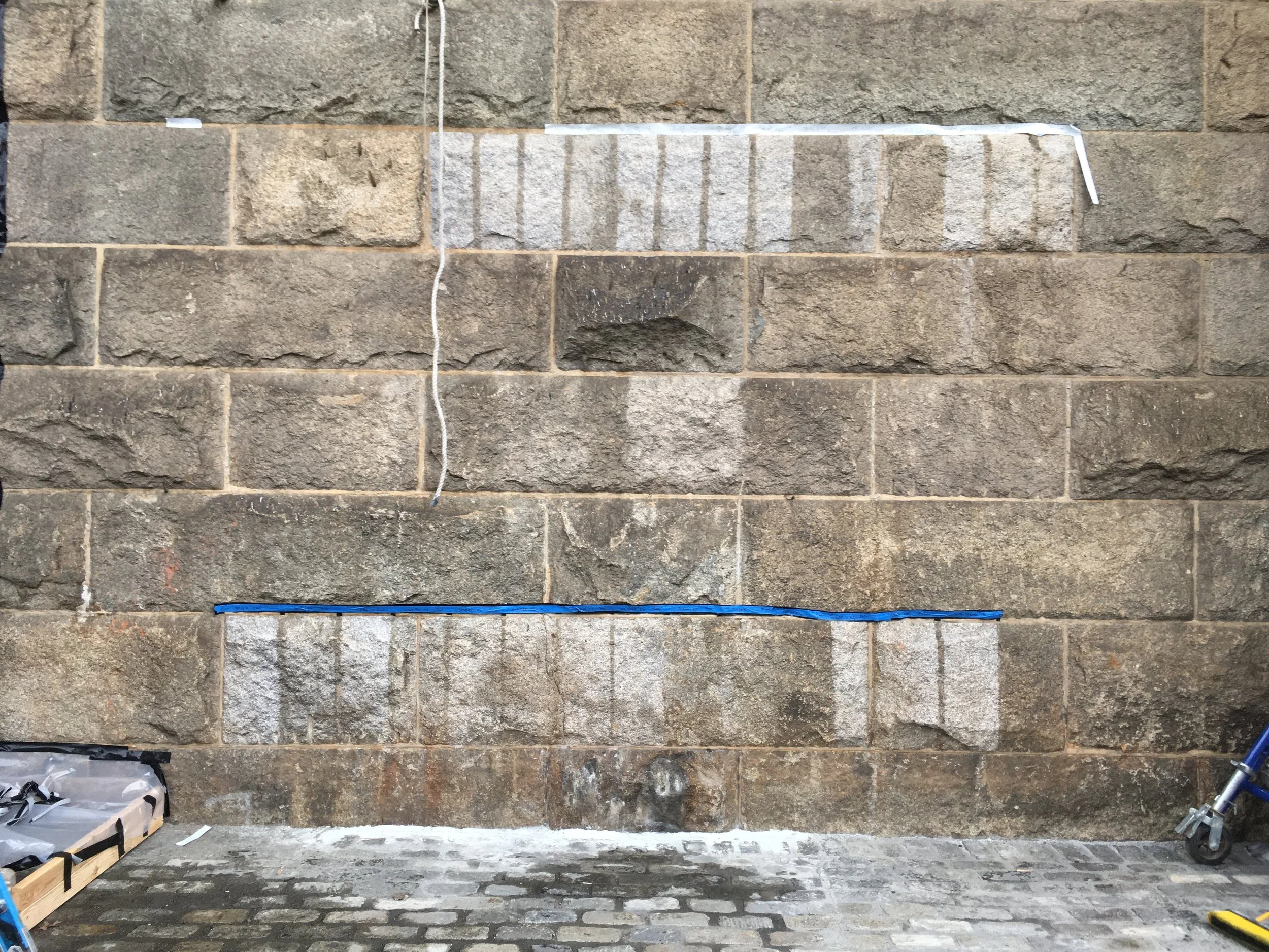 Cleaning test panels on a large granite structure.