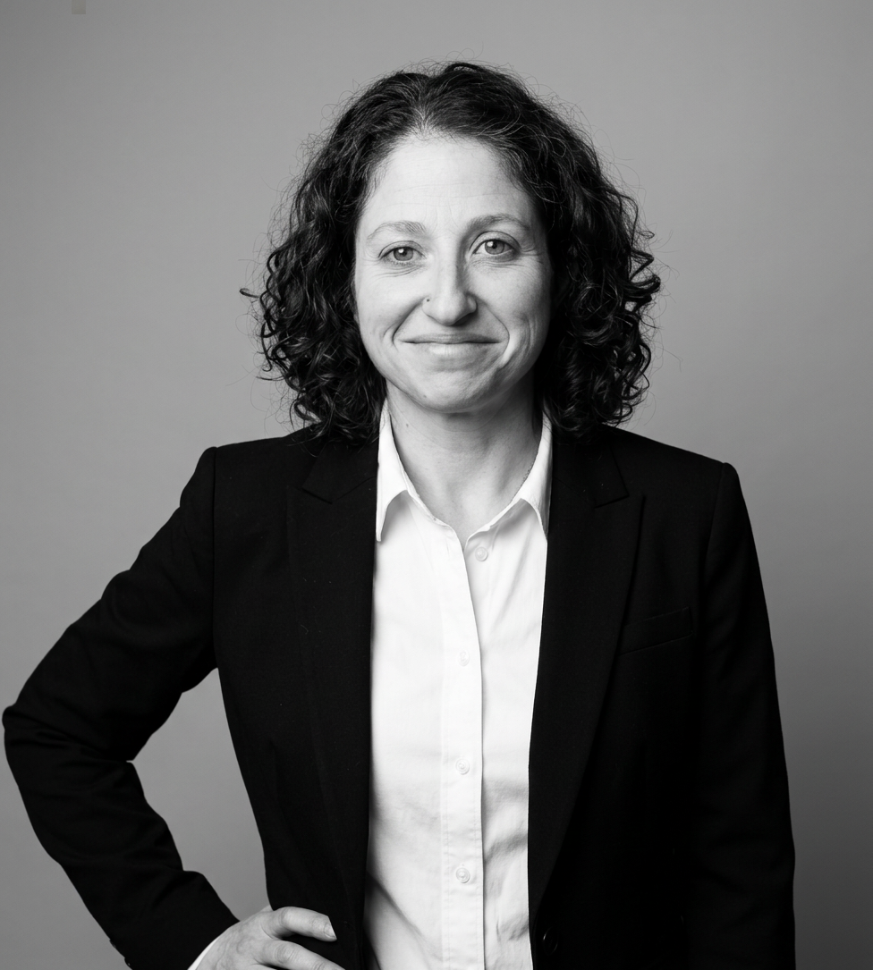 Portrait of a smiling woman with curly hair in a circular frame.