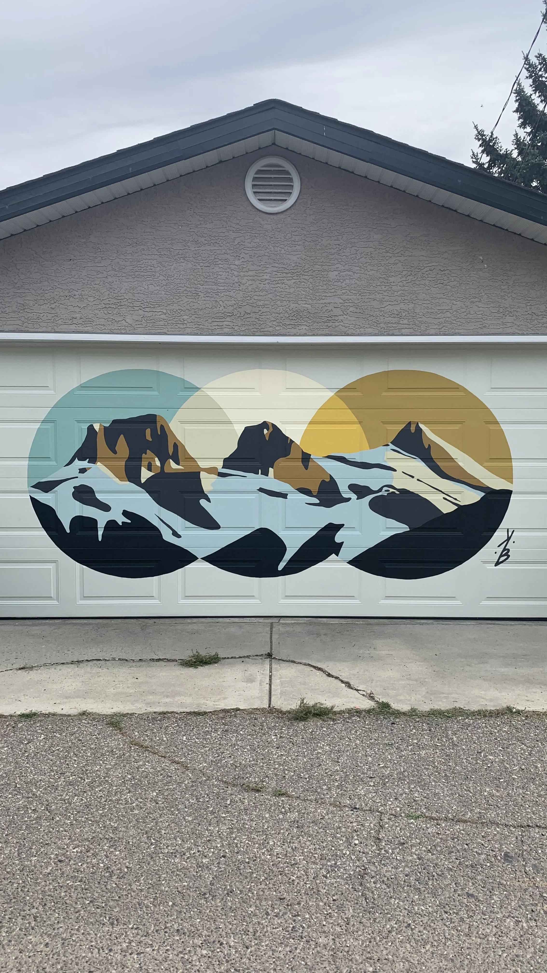 Painted mural of snow-capped mountains with two sun circles in the background on a garage door.