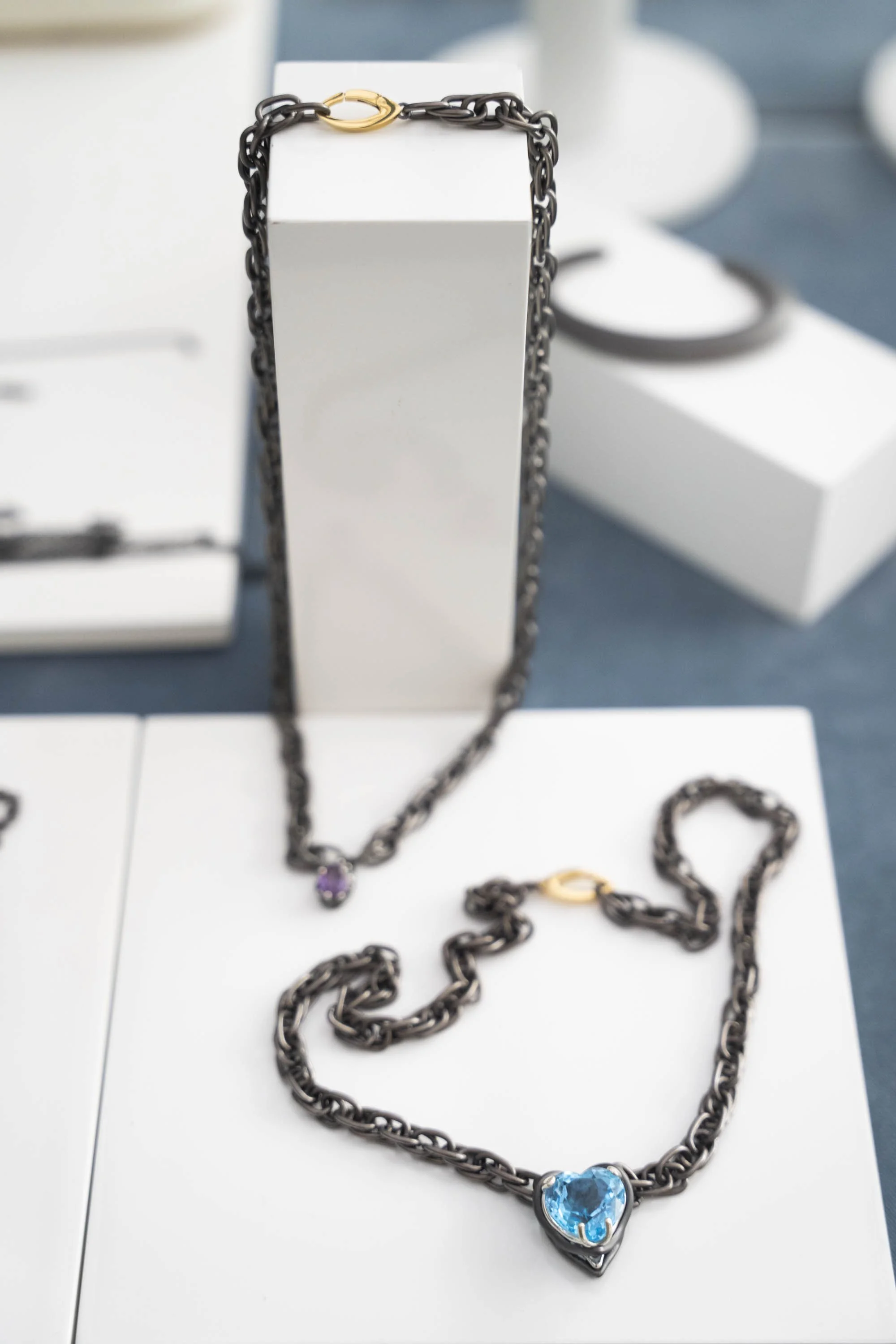 Open Heart Necklace displayed on a jewelry stand at an event table