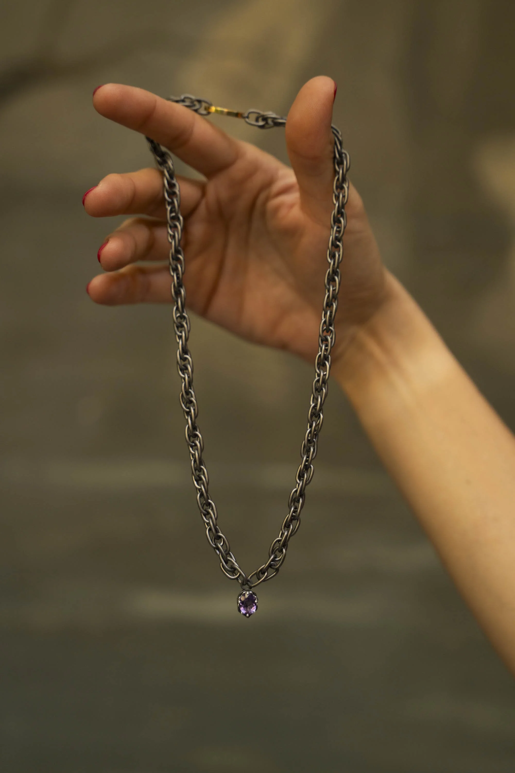 Hand holding the Twine Necklace, amethyst pendant suspended