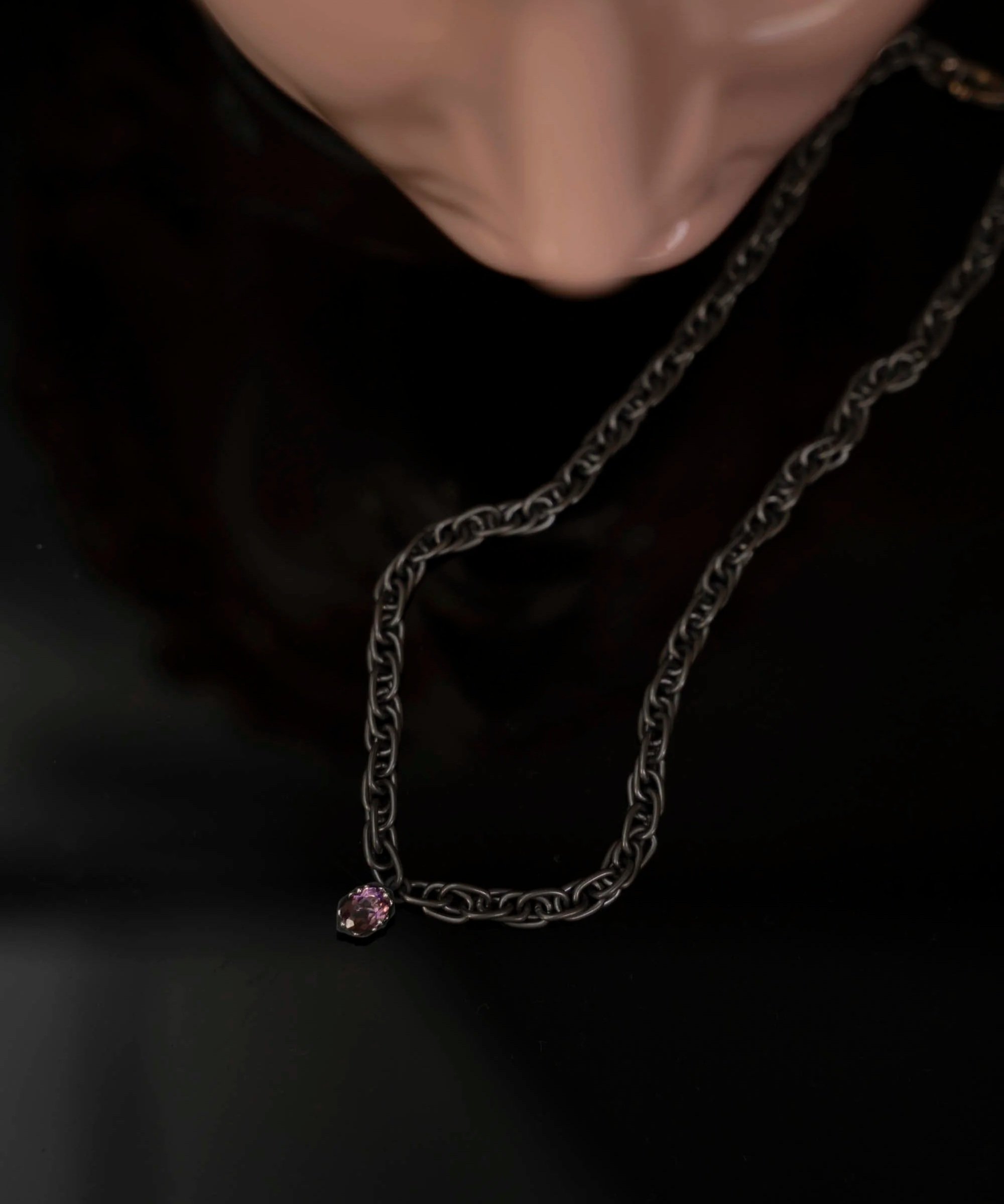 Gi by Giselle Twine Necklace, titanium and silver amethyst pendant on a table beside a statue of David, necklace in focus