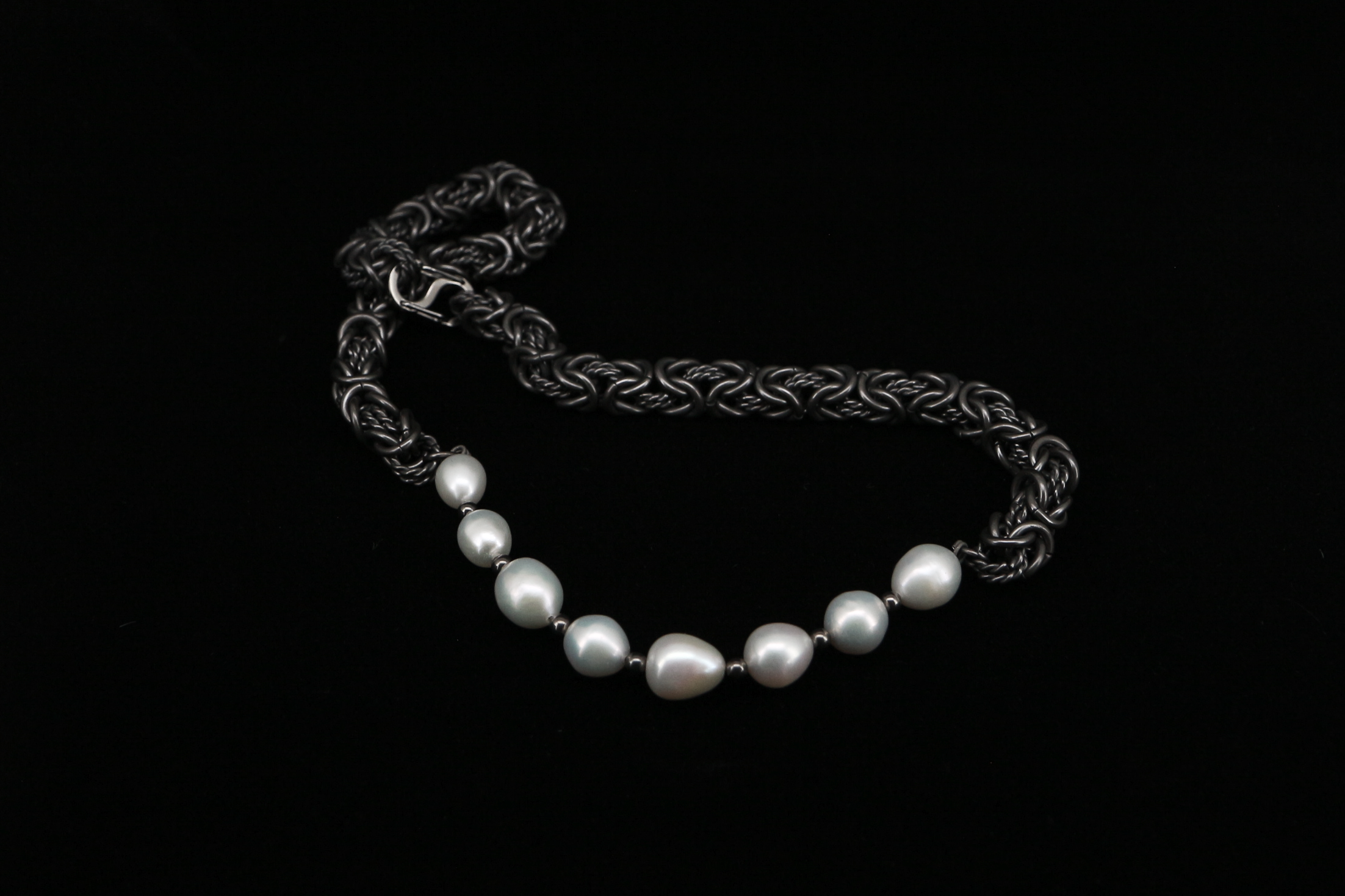 Side view of the Dew Necklace, titanium Byzantine chain stretched out showing the weave