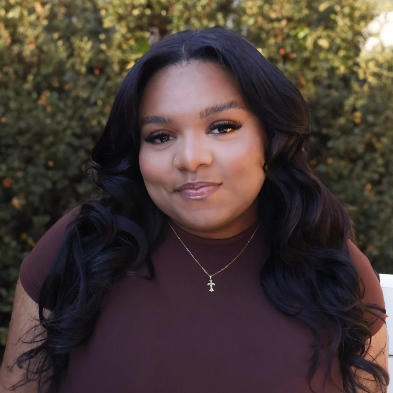headshot of a smiling woman with long hair and jewelry