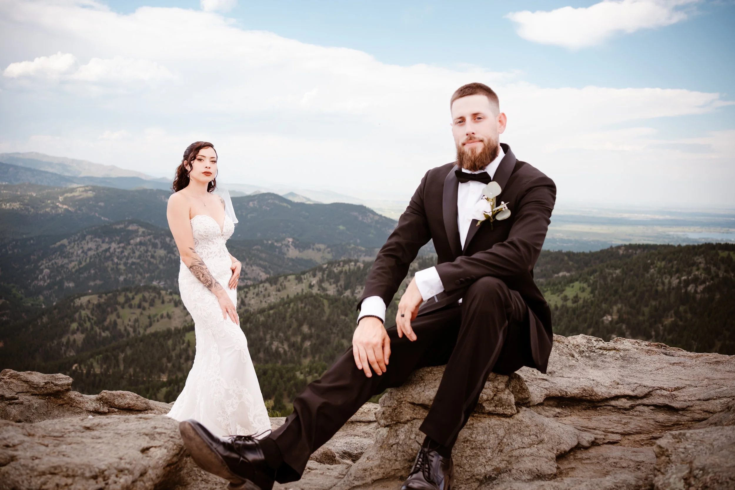 bride and groom sitting on top of mountain