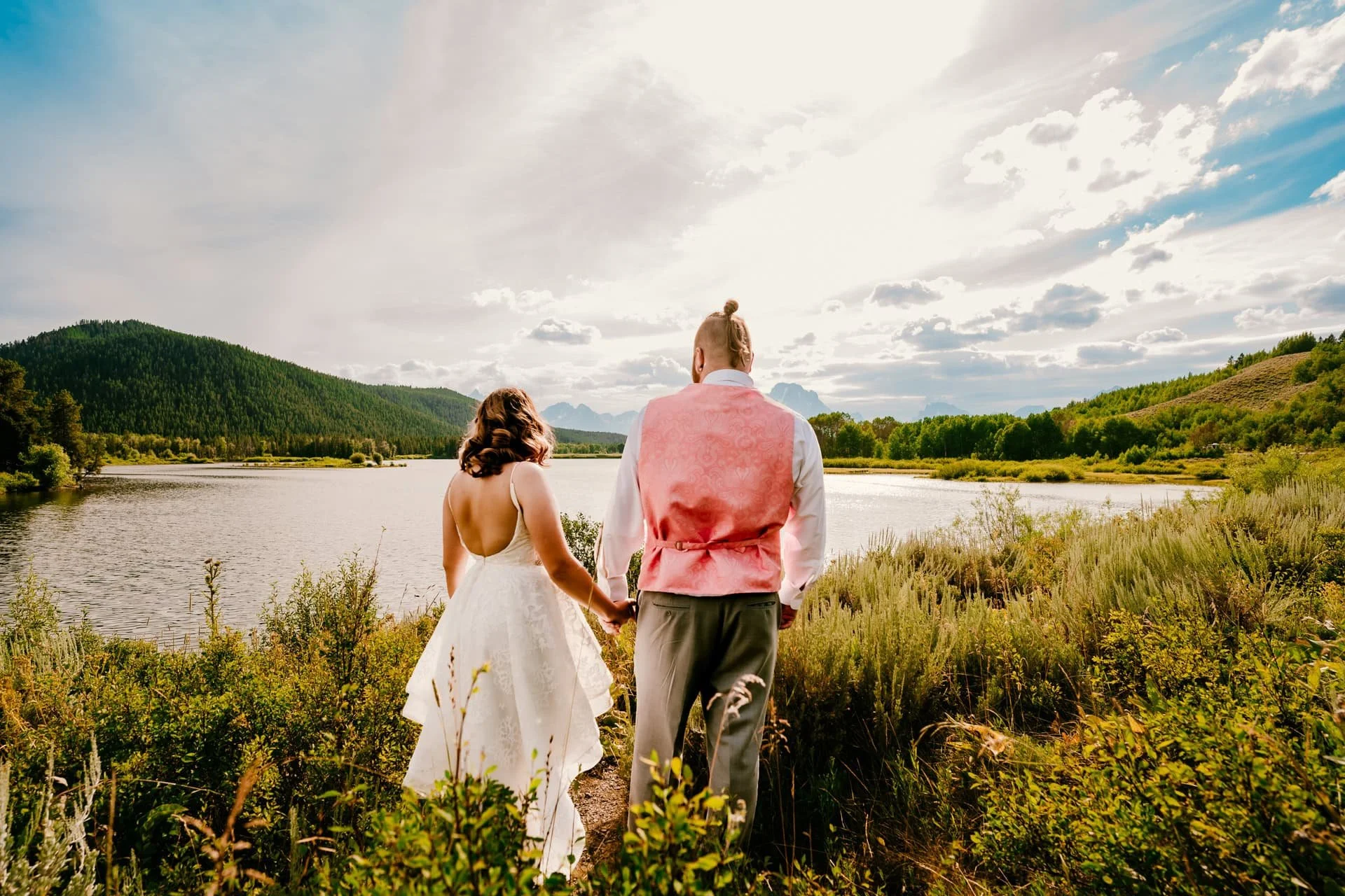 Bride and groom looking out across a lake at mountain backdrop