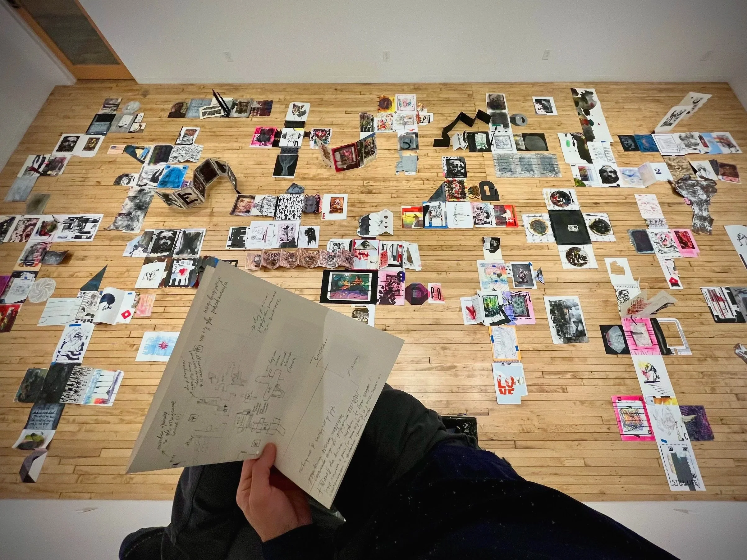 Taking notes while observing the 'Hopscotch' project laid out for the first time in an empty gallery space, Dec 2024.