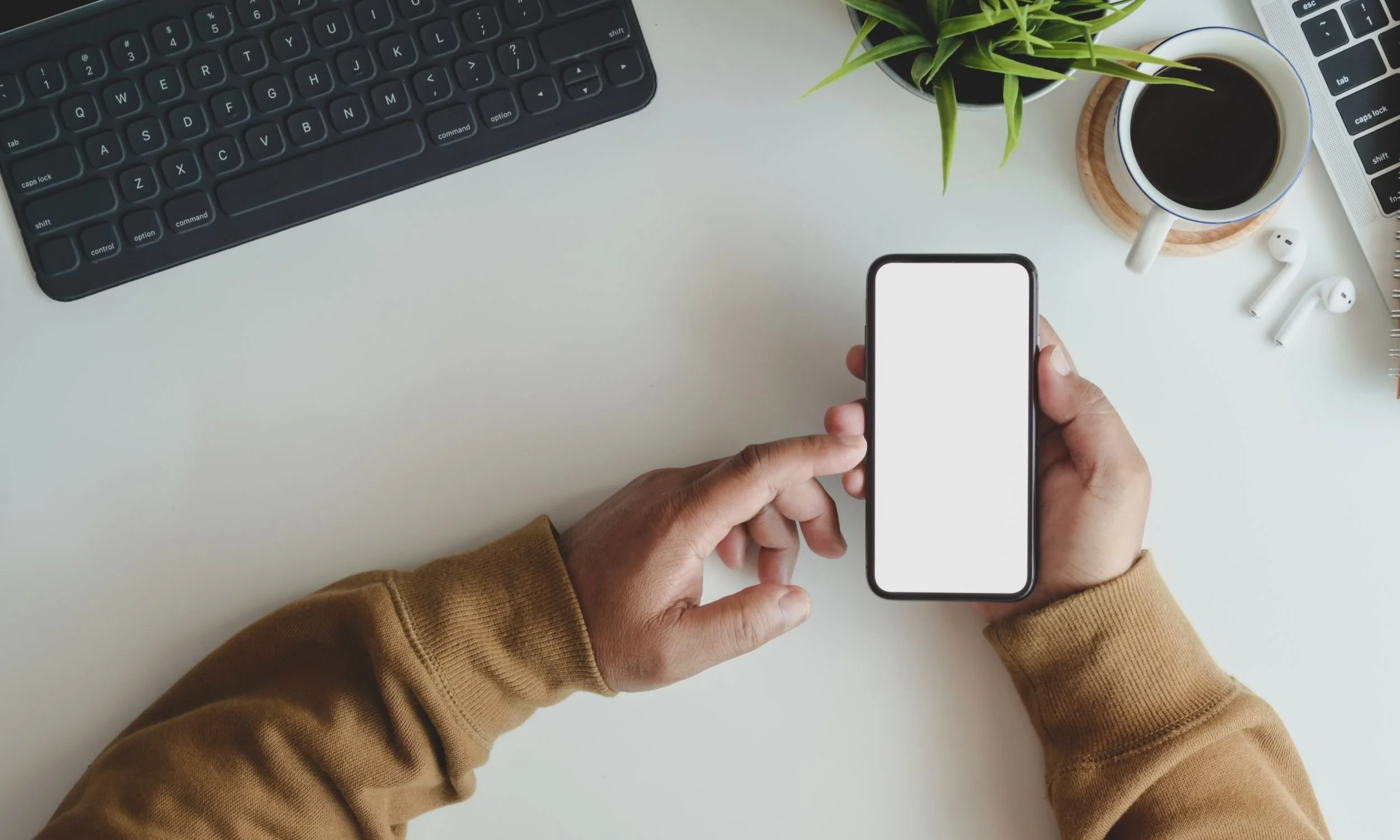 Hand holding a cellphone with a white screen.