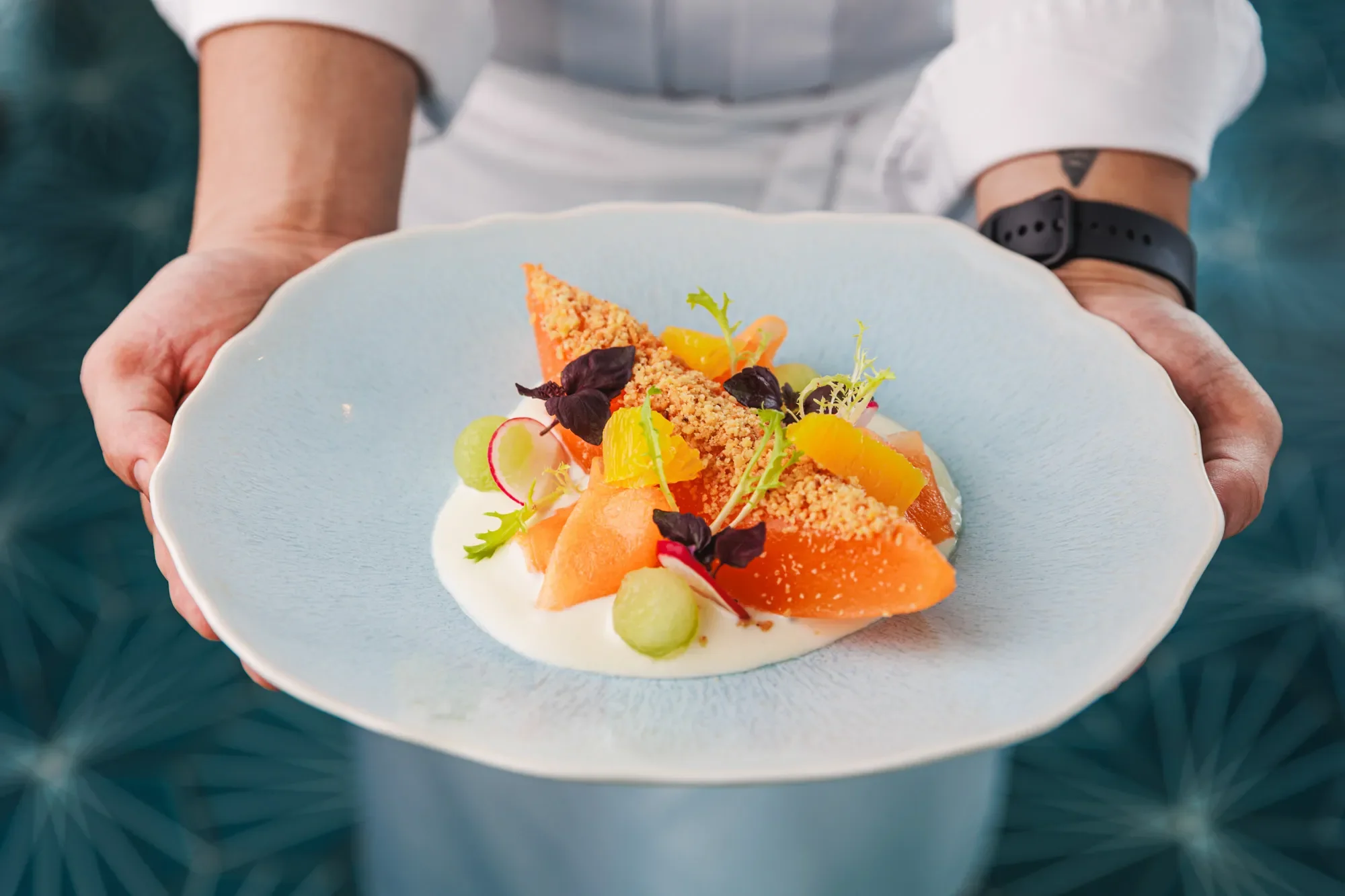 Plating of an intricate gourmet melon dish in a high-end Dubai restaurant