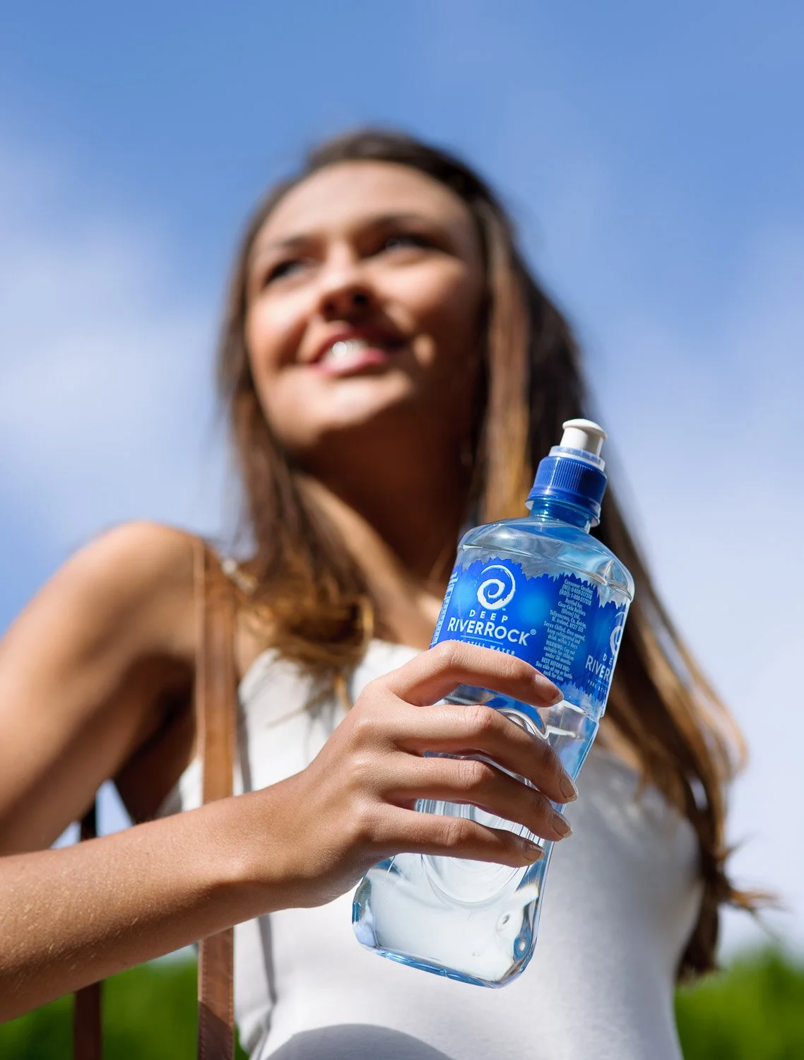 Woman drinking Deep RiverRock bottled water outdoors during a lifestyle commercial photography shoot for Coca-Cola.