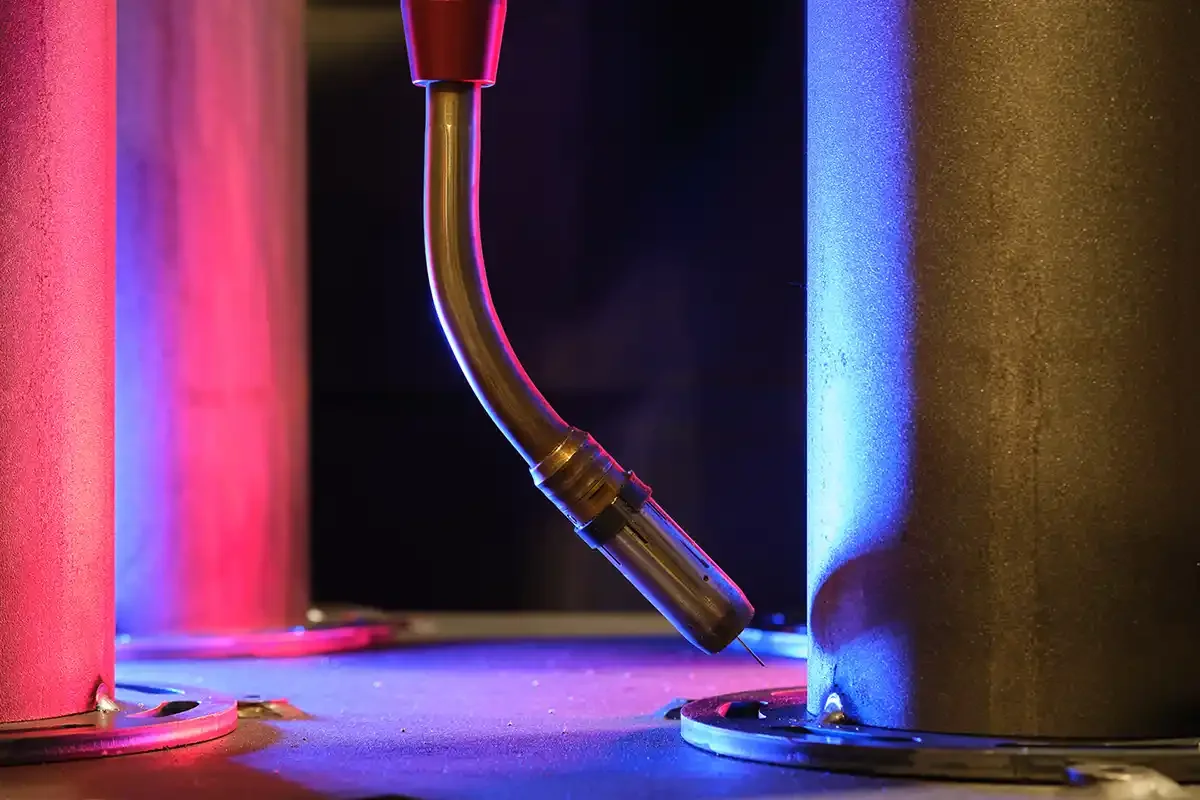 Netherlands-based Valk Welding robotic welder with articulated arm in a manufacturing facility, featuring atmospheric red and blue side lighting that creates a high-tech industrial ambiance